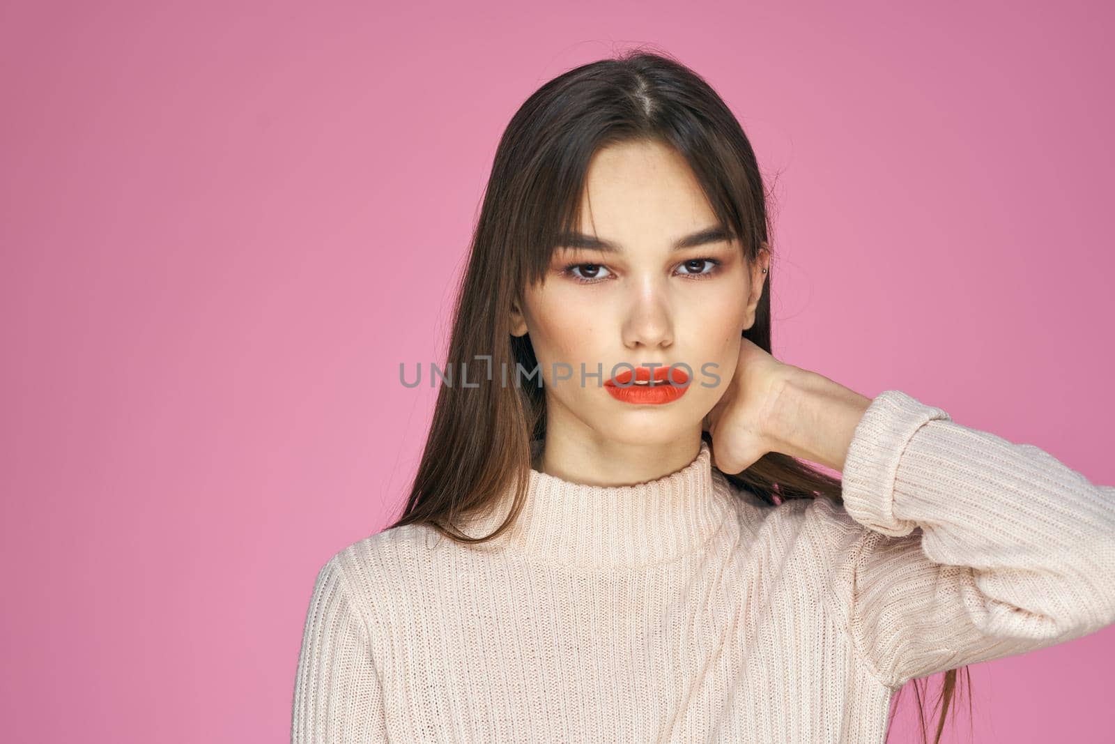 Pretty brunette in a white sweater red lips attractive look pink background by SHOTPRIME