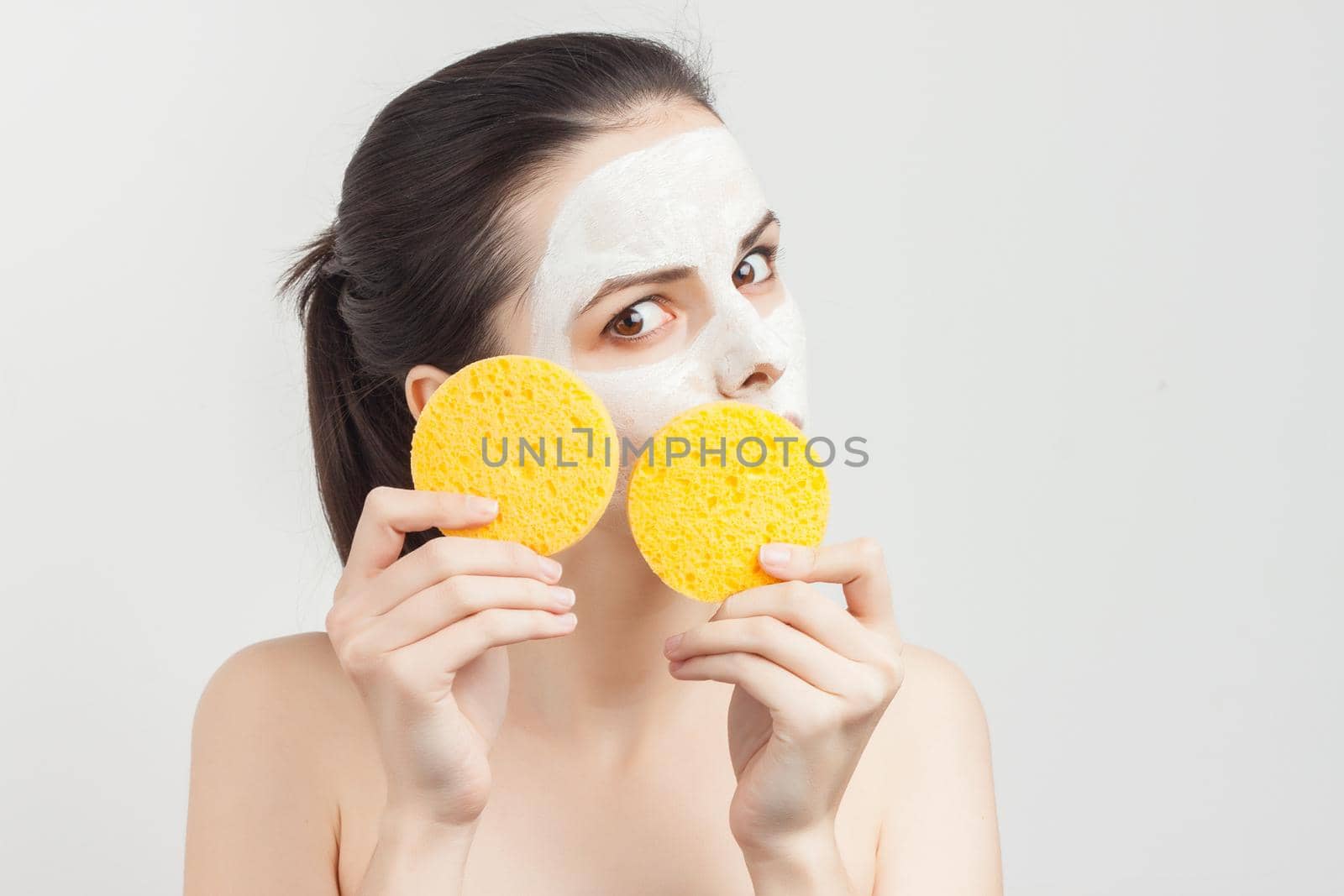 pretty woman with bare shoulders with bum in hands removing mask from face by SHOTPRIME