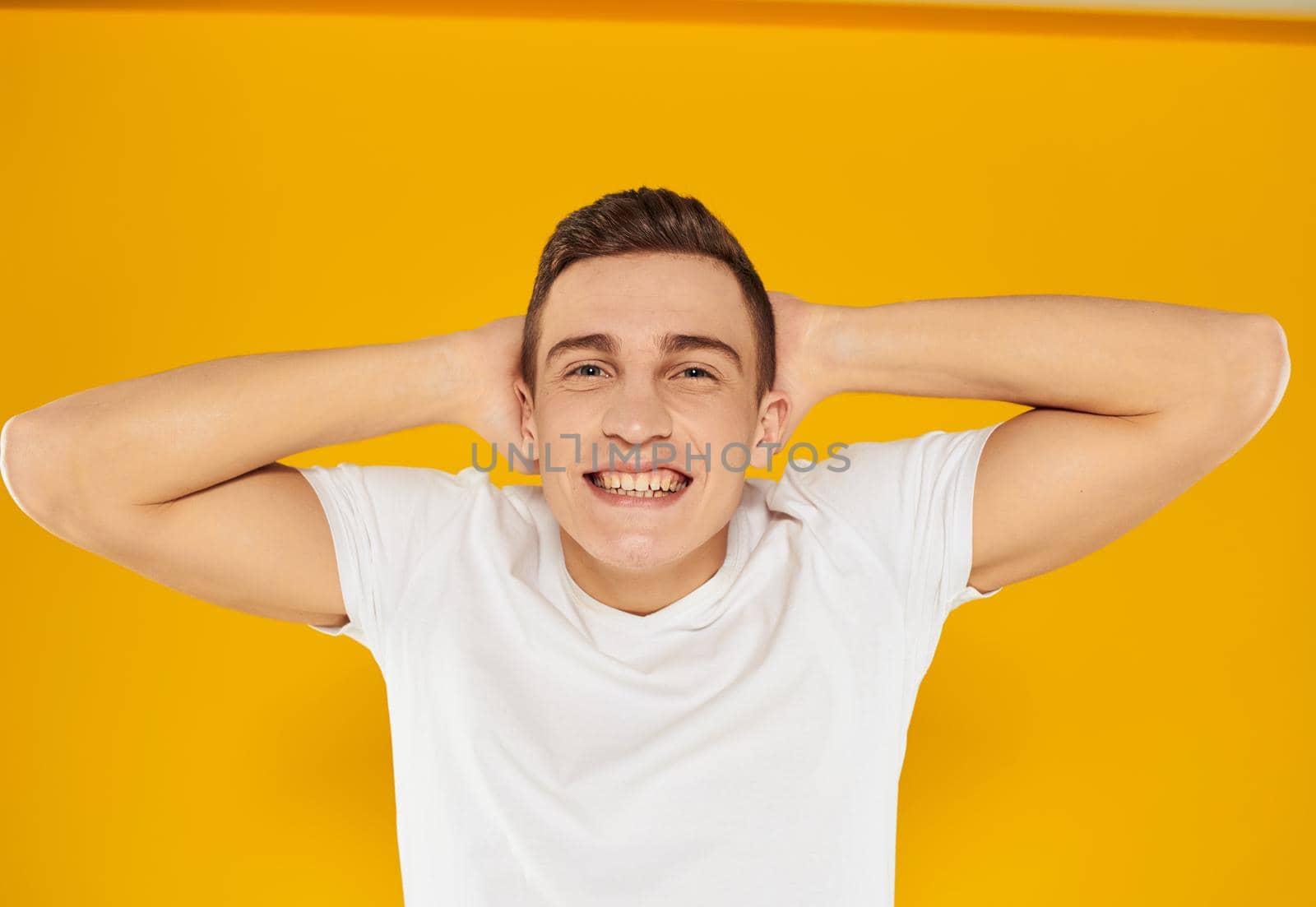 Man gesturing with his hands near the face emotions model yellow background by SHOTPRIME