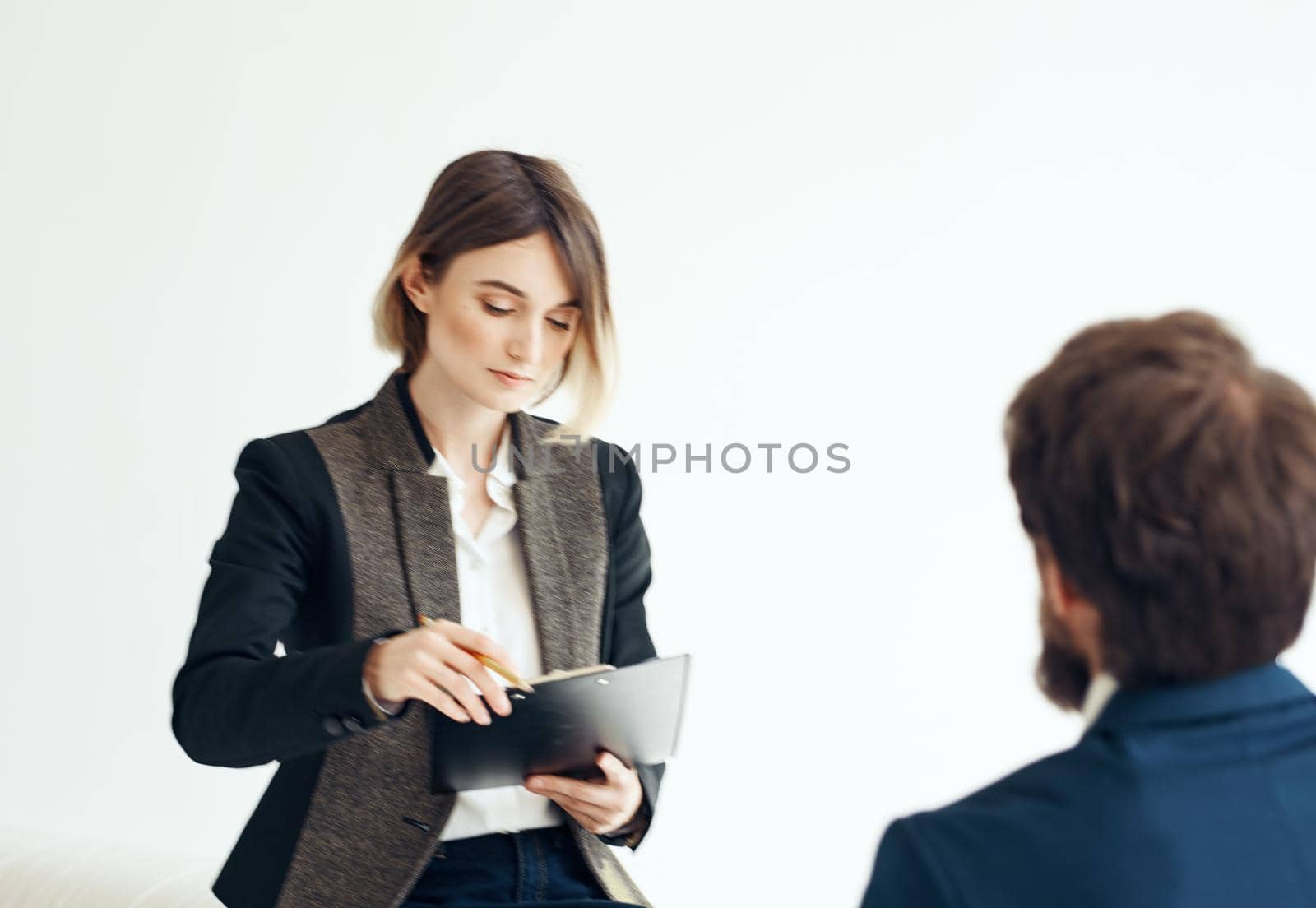 A man for an interview In a bright room talking to a woman opposite by SHOTPRIME