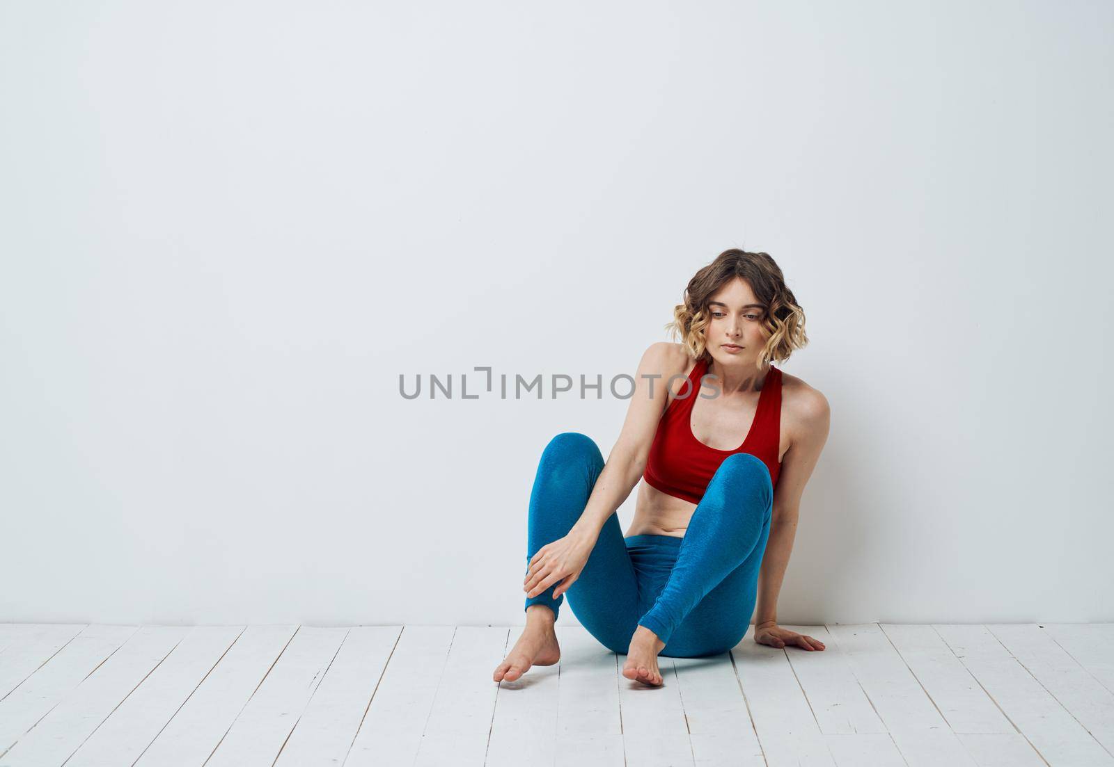 woman in blue leggings doing sports on a light floor indoors in full growth. High quality photo