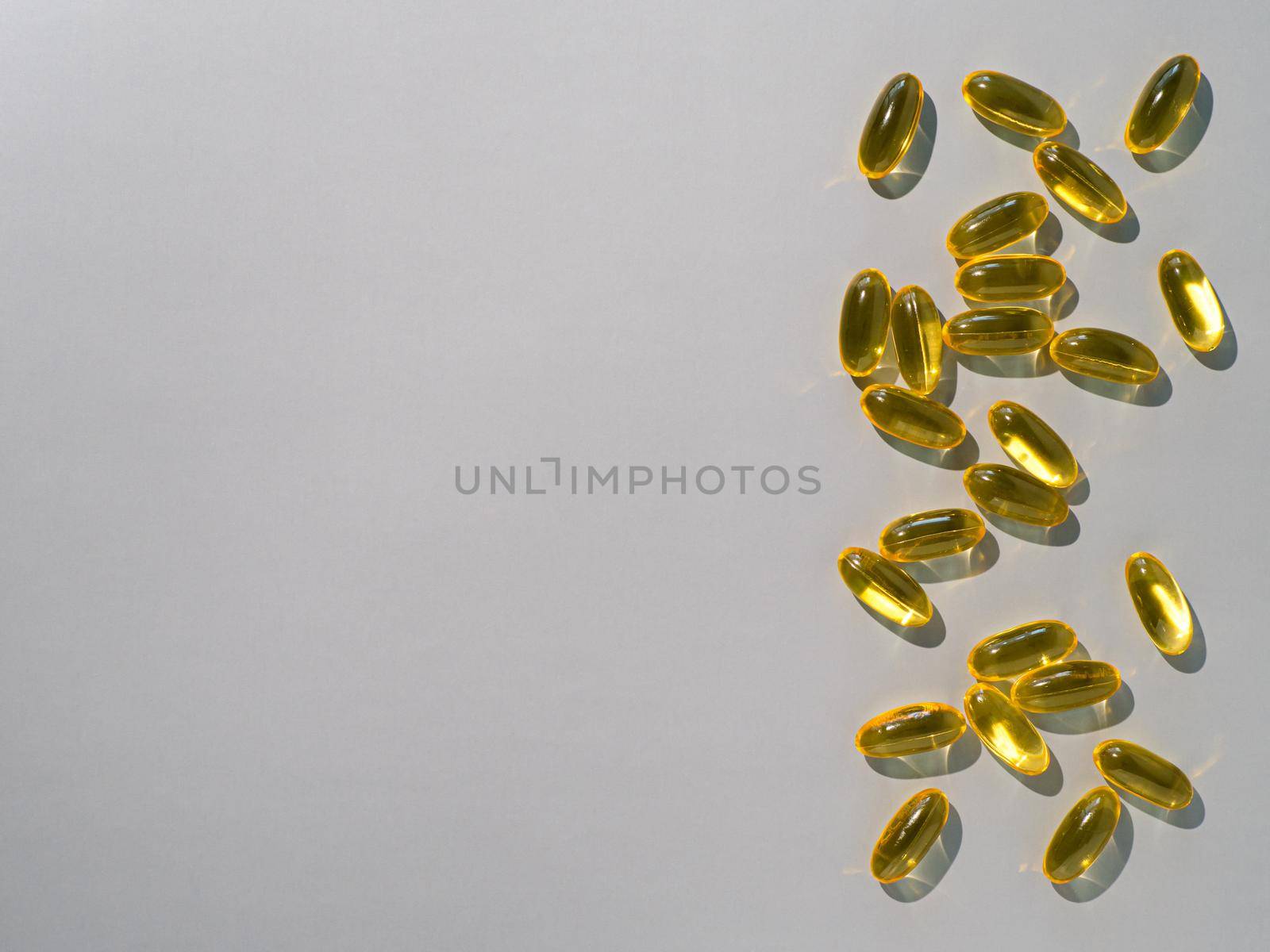 Vitamin D3, Omega or Evening Primula Oil gel capsules on neutral gray background. Top view or flat lay yellow liquid capsules with nutritional supplement oil. Copy space for text.