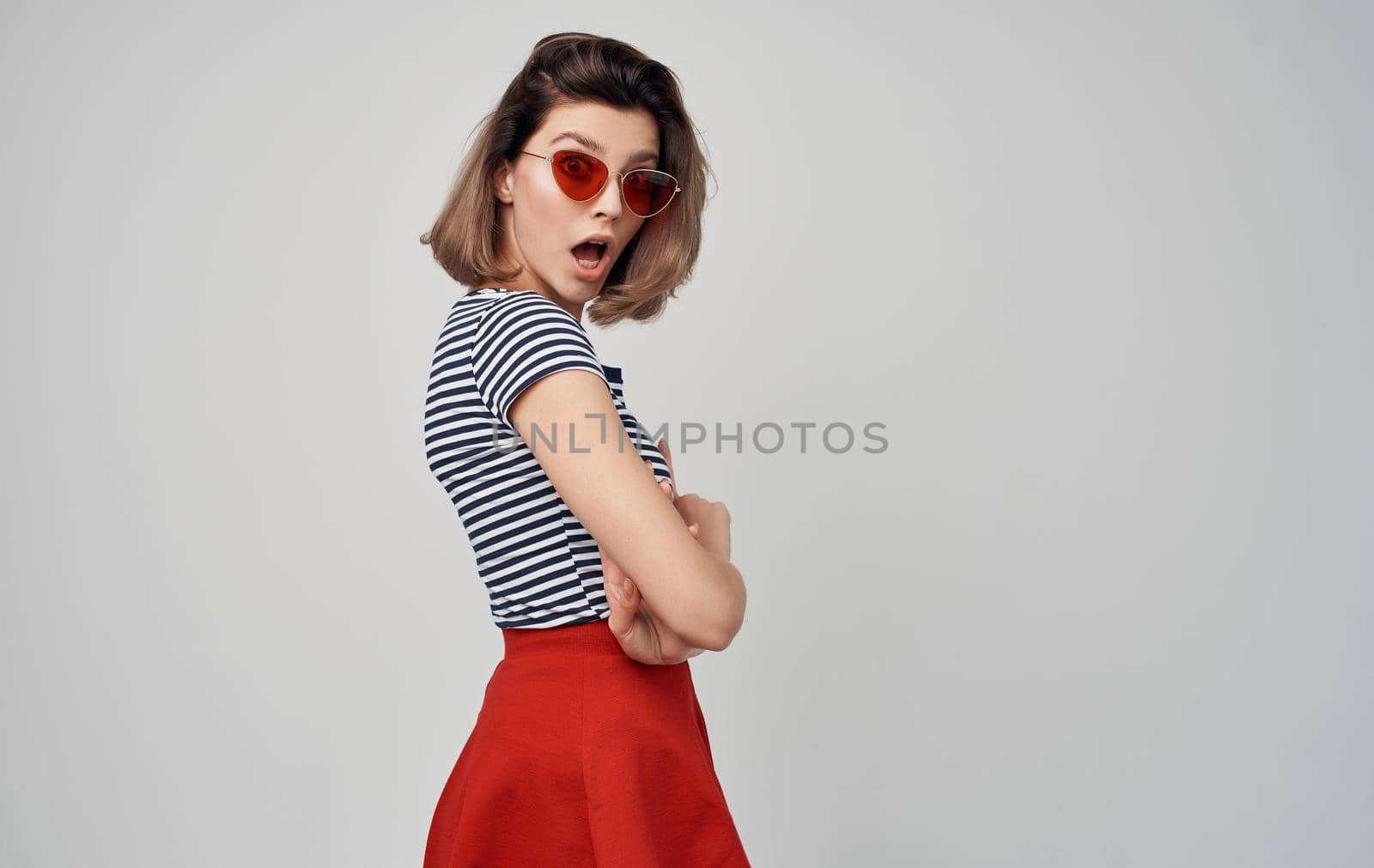 beautiful woman with glasses and striped t-shirt red skirt gray background by SHOTPRIME