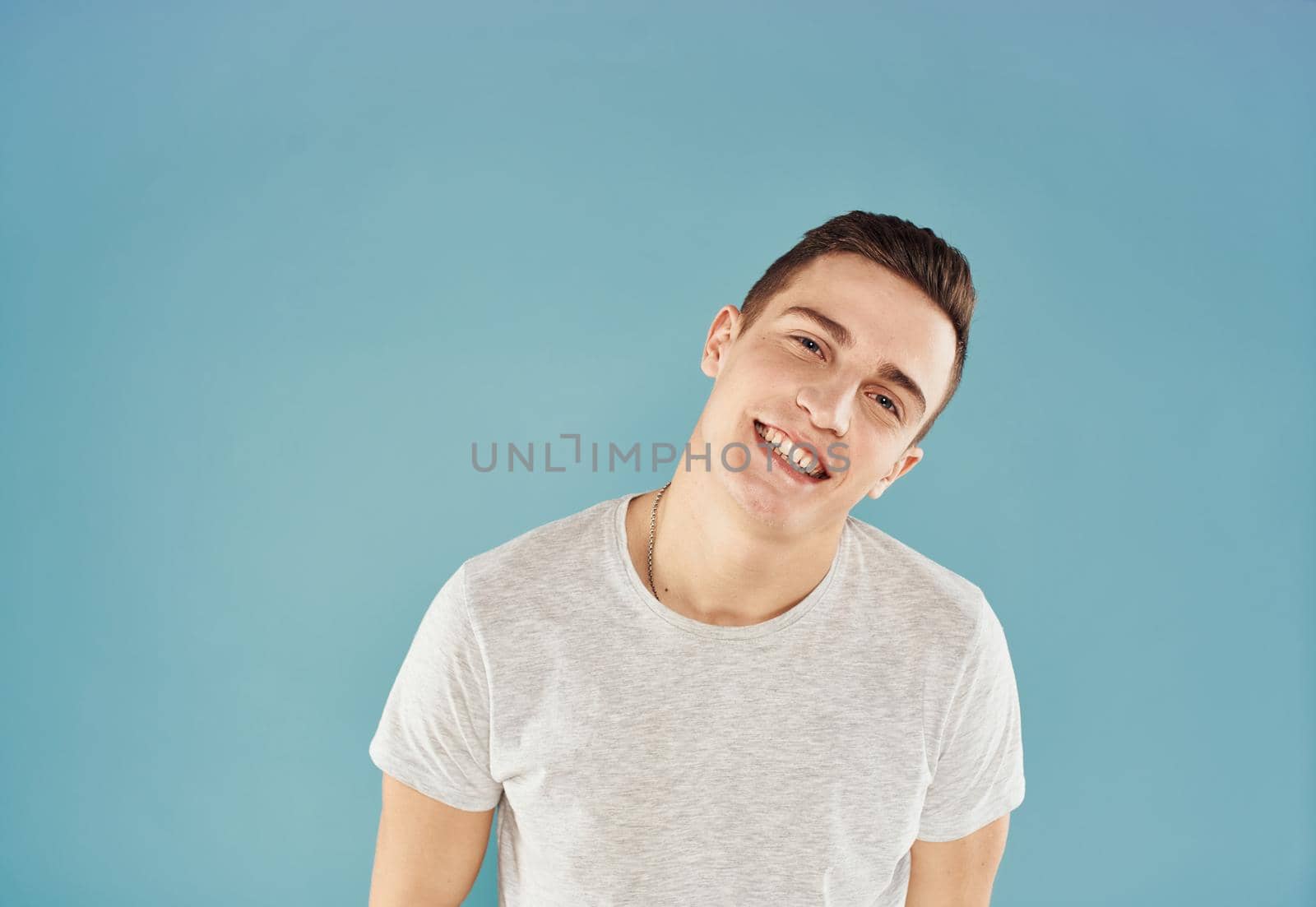 Cheerful man in white T-shirt emotions gestures with hands blue background by SHOTPRIME