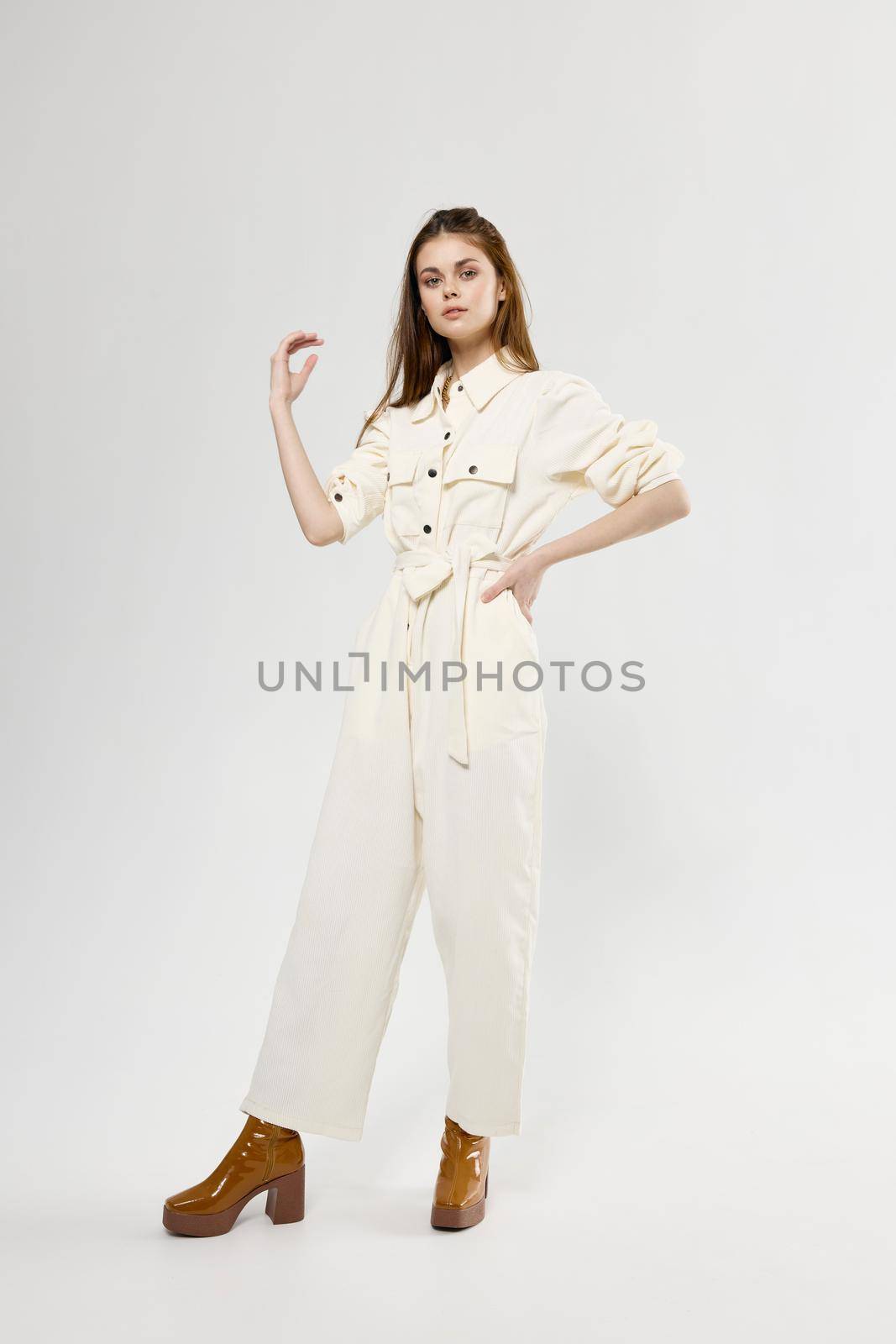 shopping fashionable woman in a white boot jumpsuit on a light background gestures with her hands. High quality photo