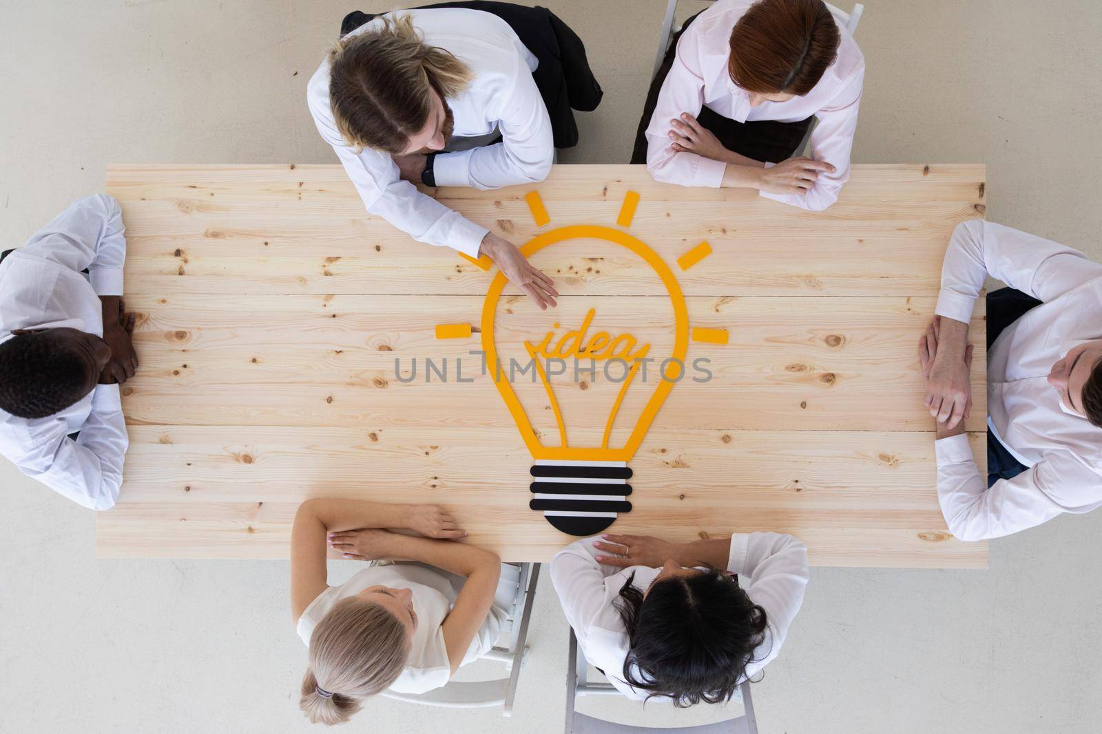 Team of business people pointing idea bulb icon at meeting table strategic marketing creative idea strategy development concept