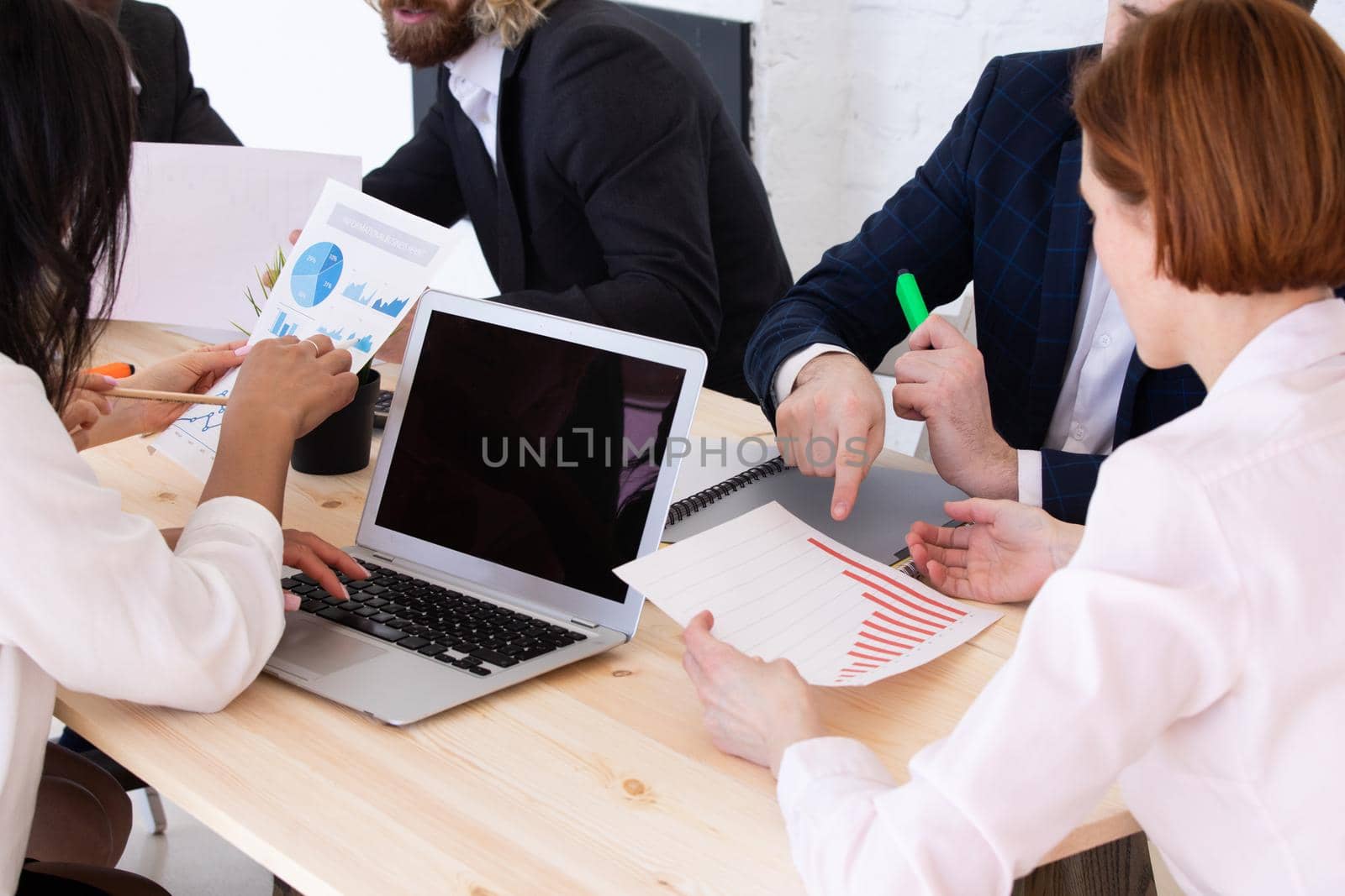 Diverse executive business people team discussing work results at meeting, multiracial businessmen talking analyzing financial statistics report sitting together in modern office with laptop and documents