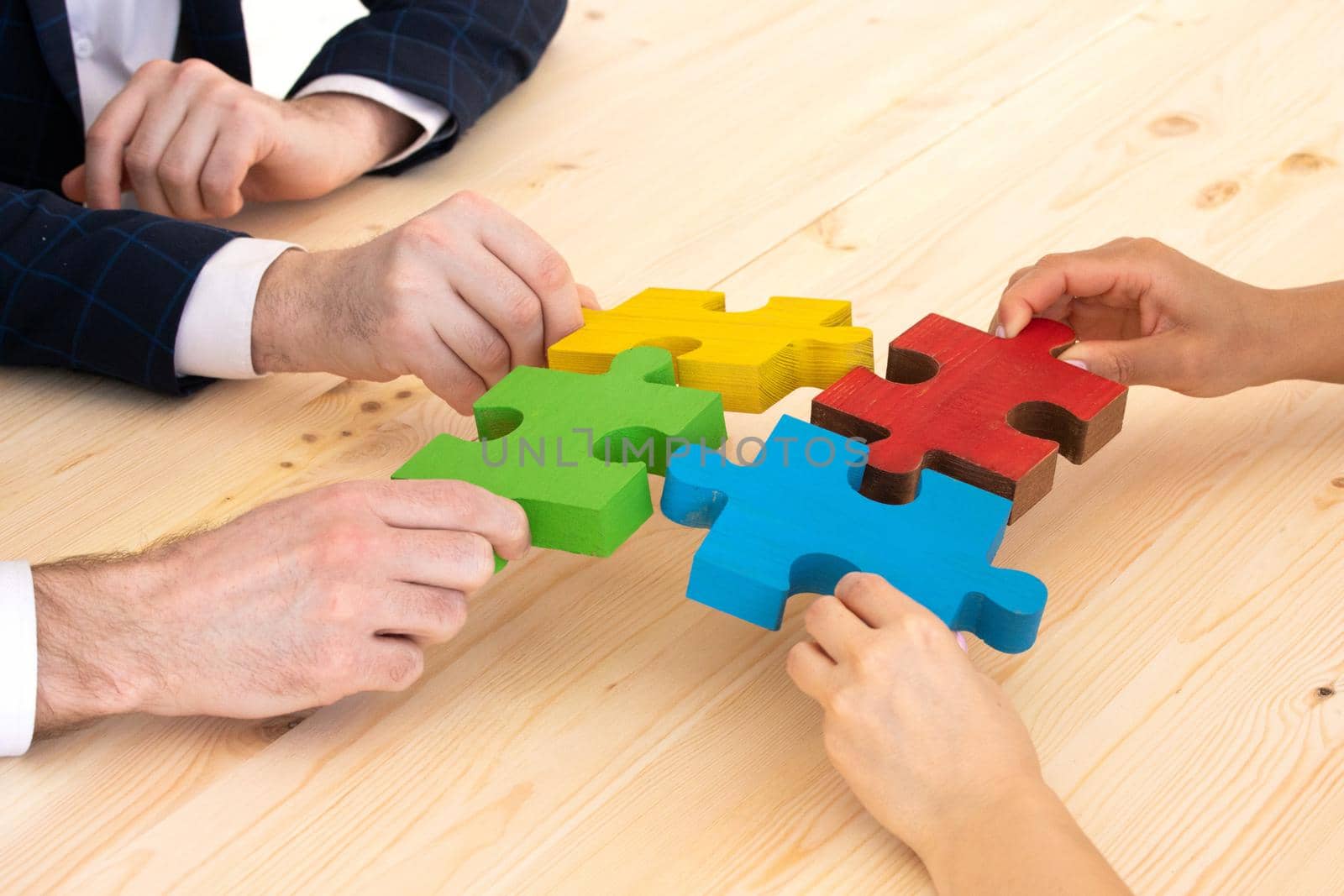 Business people team assembling four color jigsaw puzzle pieces unity cooperation ideas concept