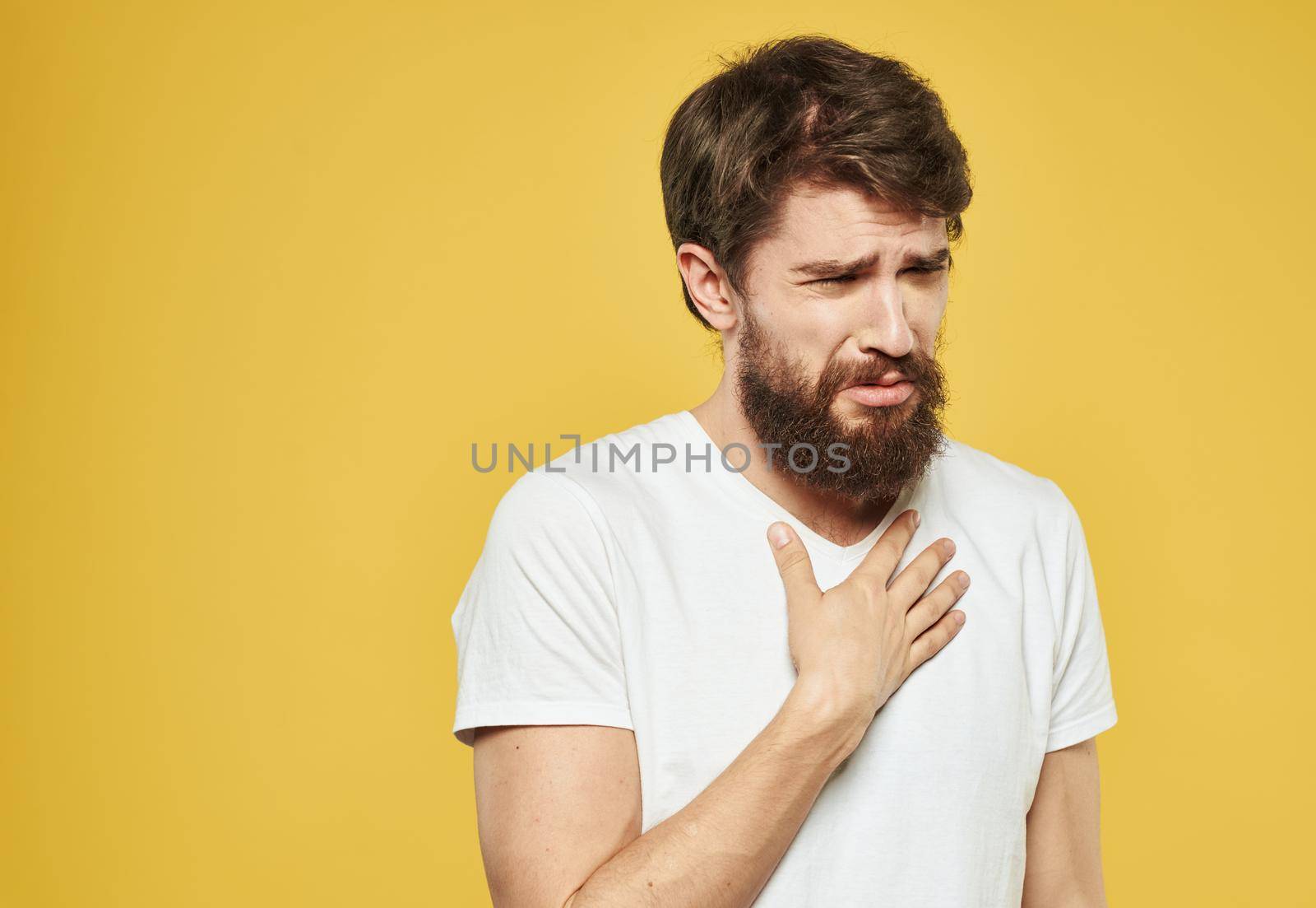 A brunette man with a thick beard on a yellow background emotions model. High quality photo