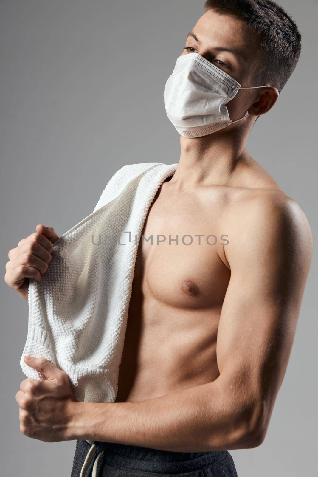 sporty man in medical mask towel on shoulders pumped up body by SHOTPRIME