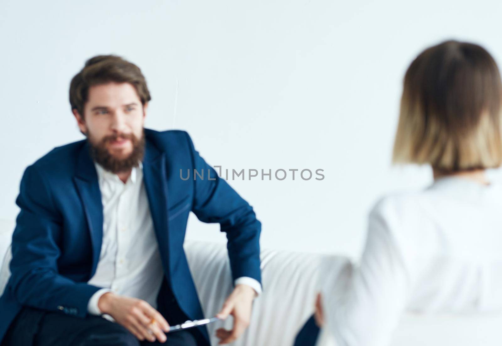 A man in a classic suit sits on the couch indoors with documents and a woman vacancies. High quality photo