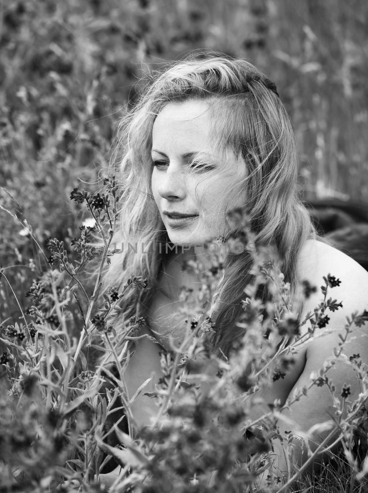Black and white portrait of freckled woman on natural background. Young woman enjoying nature among the flowers and grass. Close up summer portrait 