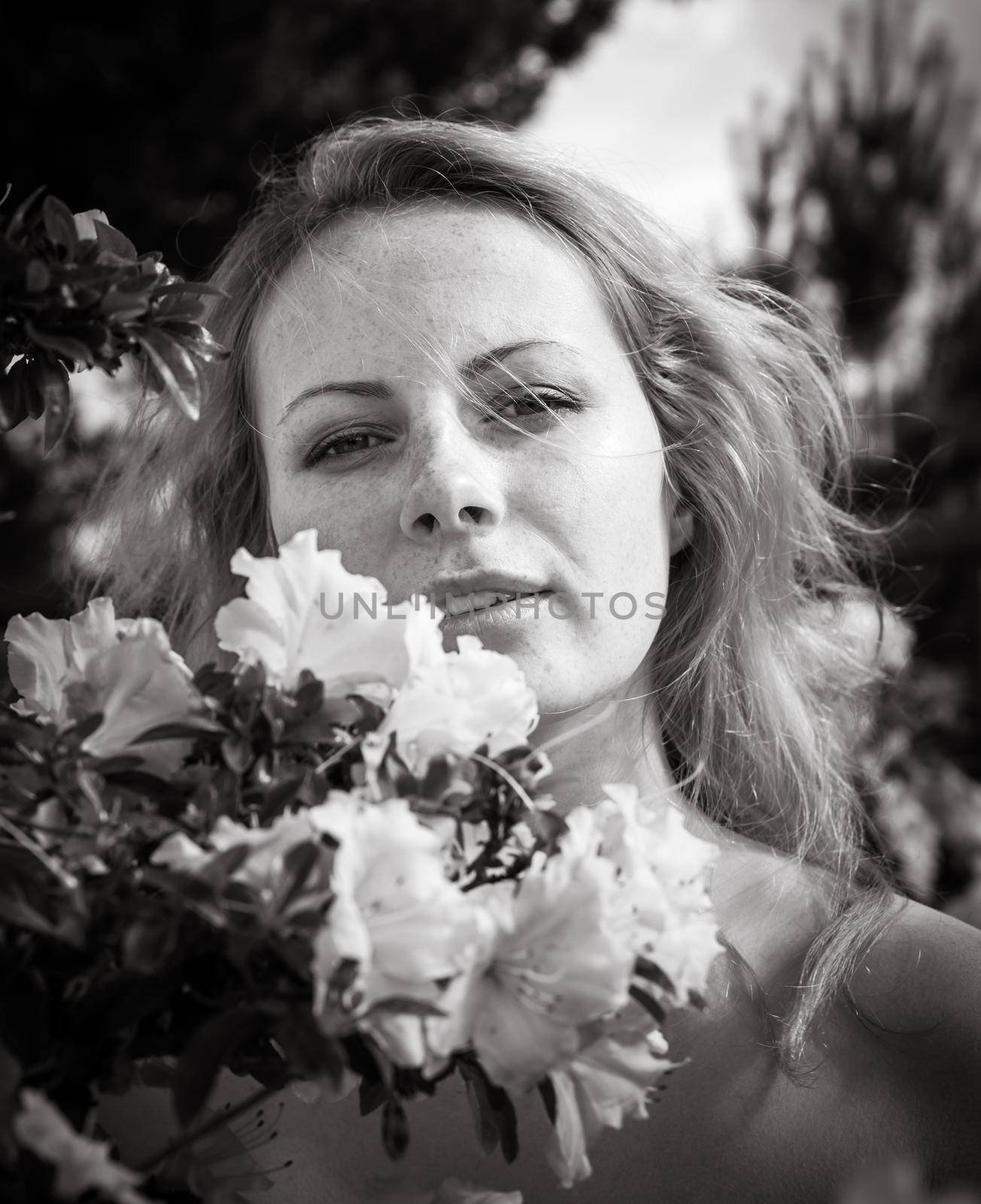 Beauty and youth concept. Portrait of a beautiful blonde young woman among the flowers of azalea