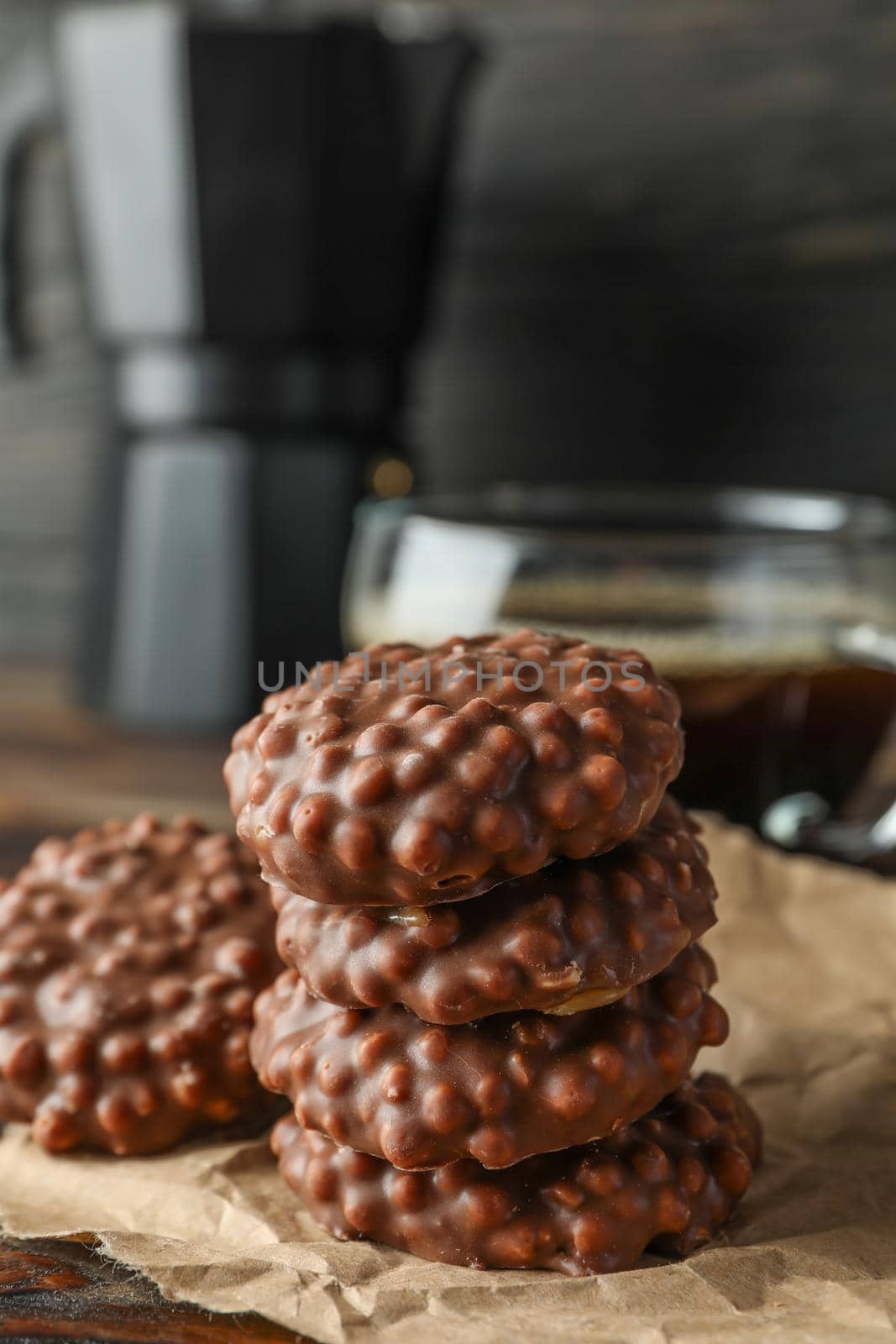 Stack of chocolate cookies and cup of coffee on wooden table against dark background, space for text