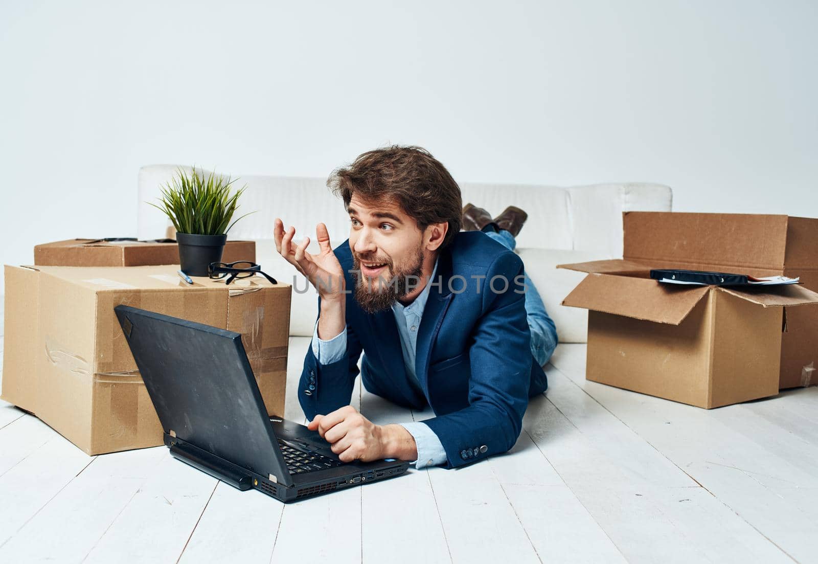 A man in a suit lies on the floor with office boxes unpacking a laptop technology. High quality photo