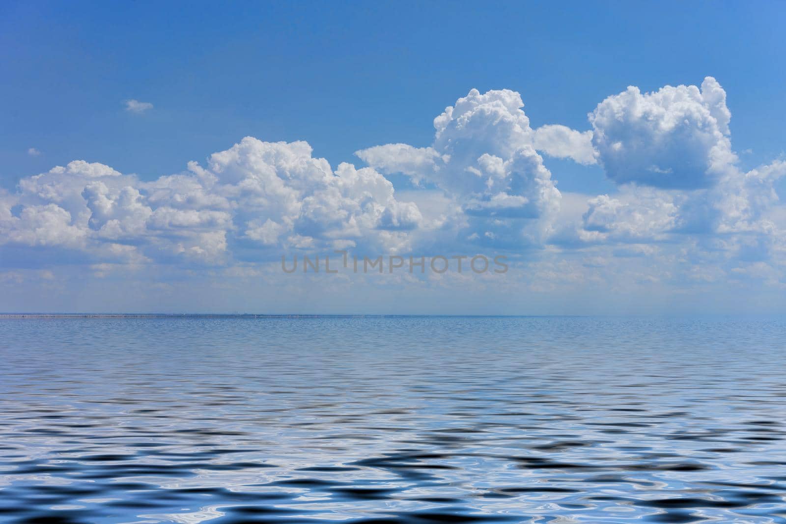 Seascape with a large pebble beach and blue sea to the horizon.
