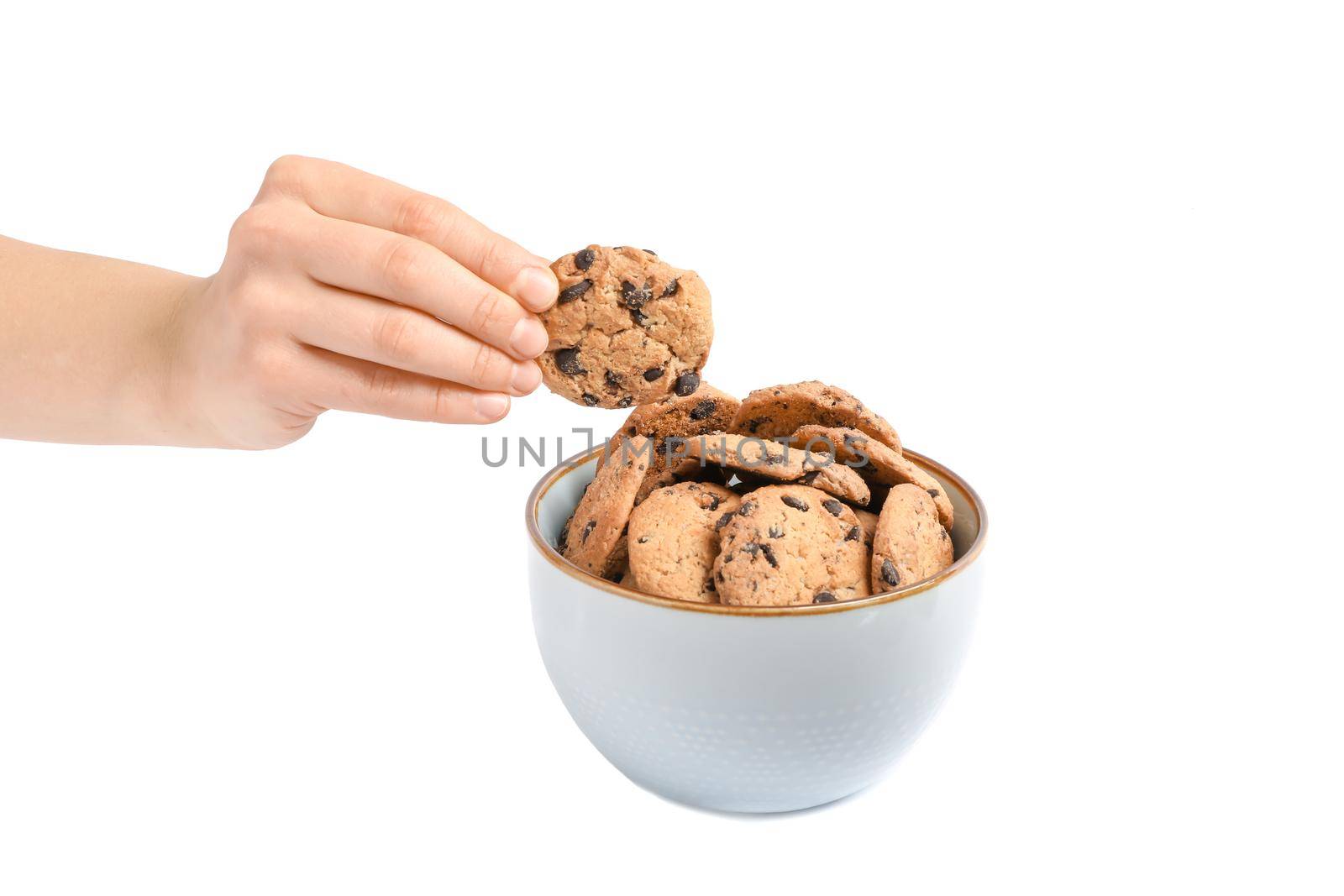 Young woman holding tasty chocolate chip cookie over bowl on white background, closeup