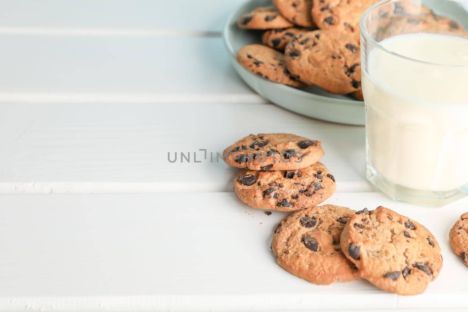 Tasty chocolate chip cookies and glass of milk on wooden table. Space for text