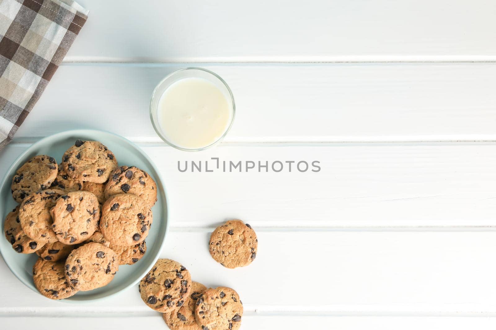 Tasty chocolate chip cookies and glass of milk on wooden table. Space for text