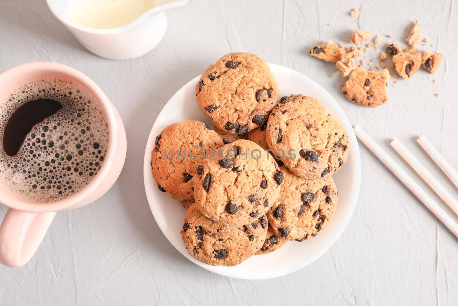 Plate with tasty chocolate chip cookies and cup of coffee on gray background, top view by AtlasCompany