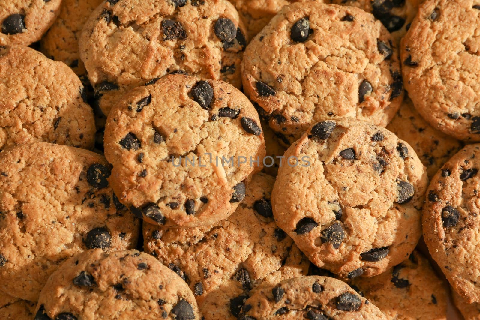 Tasty chocolate chip cookies as background, top view