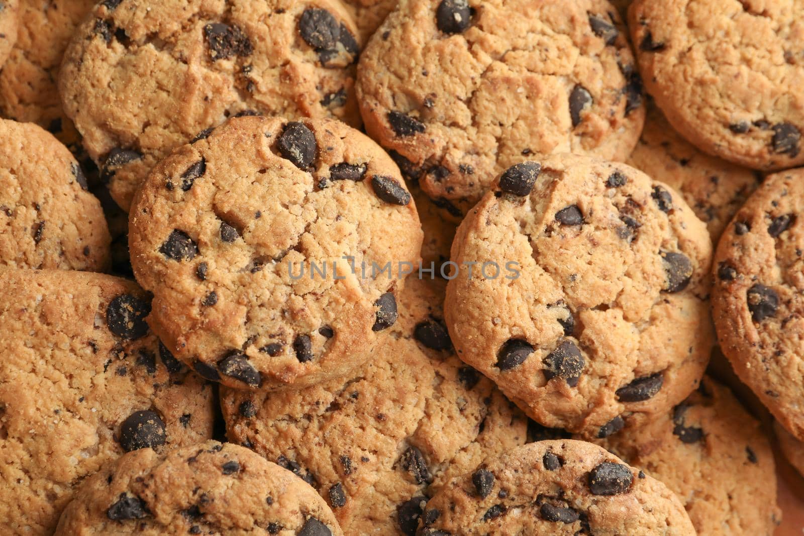 Tasty chocolate chip cookies as background, top view