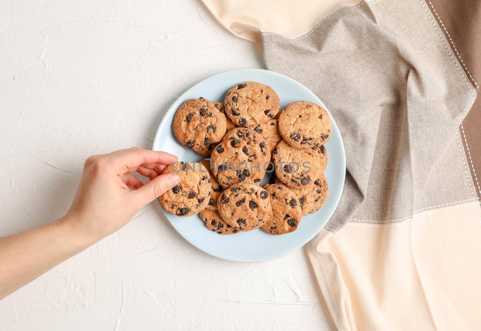 Woman with tasty chocolate chip cookies on gray background, top view. Space for text by AtlasCompany