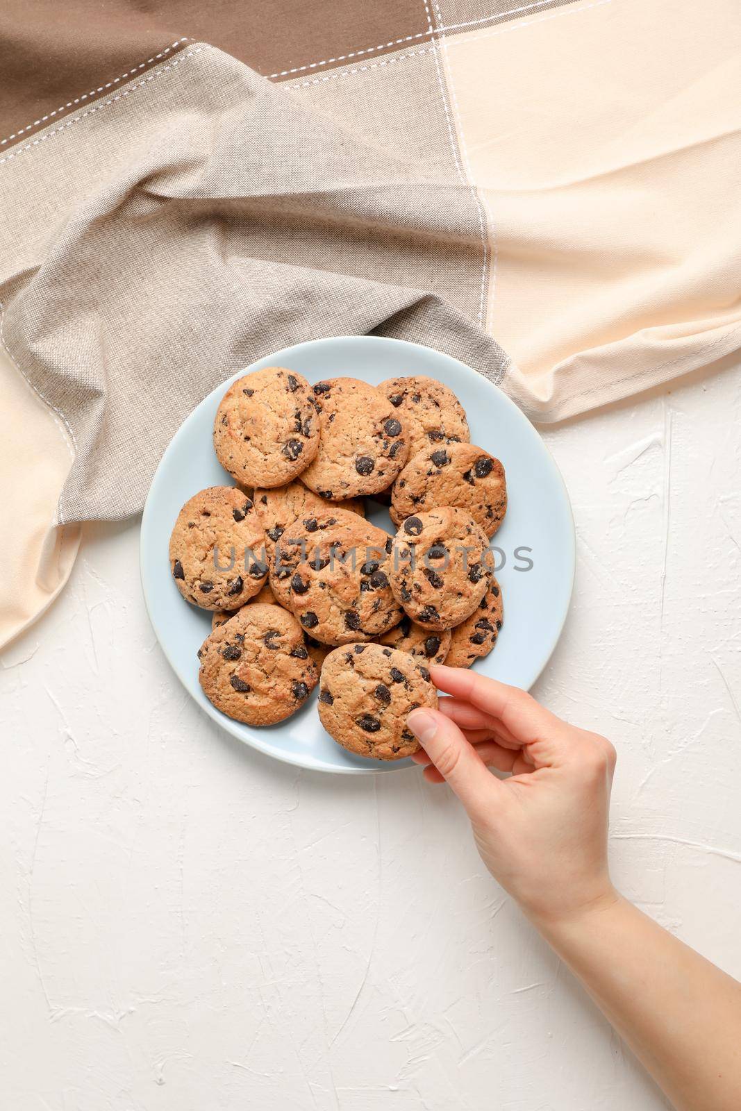 Woman with tasty chocolate chip cookies on gray background, top view. Space for text