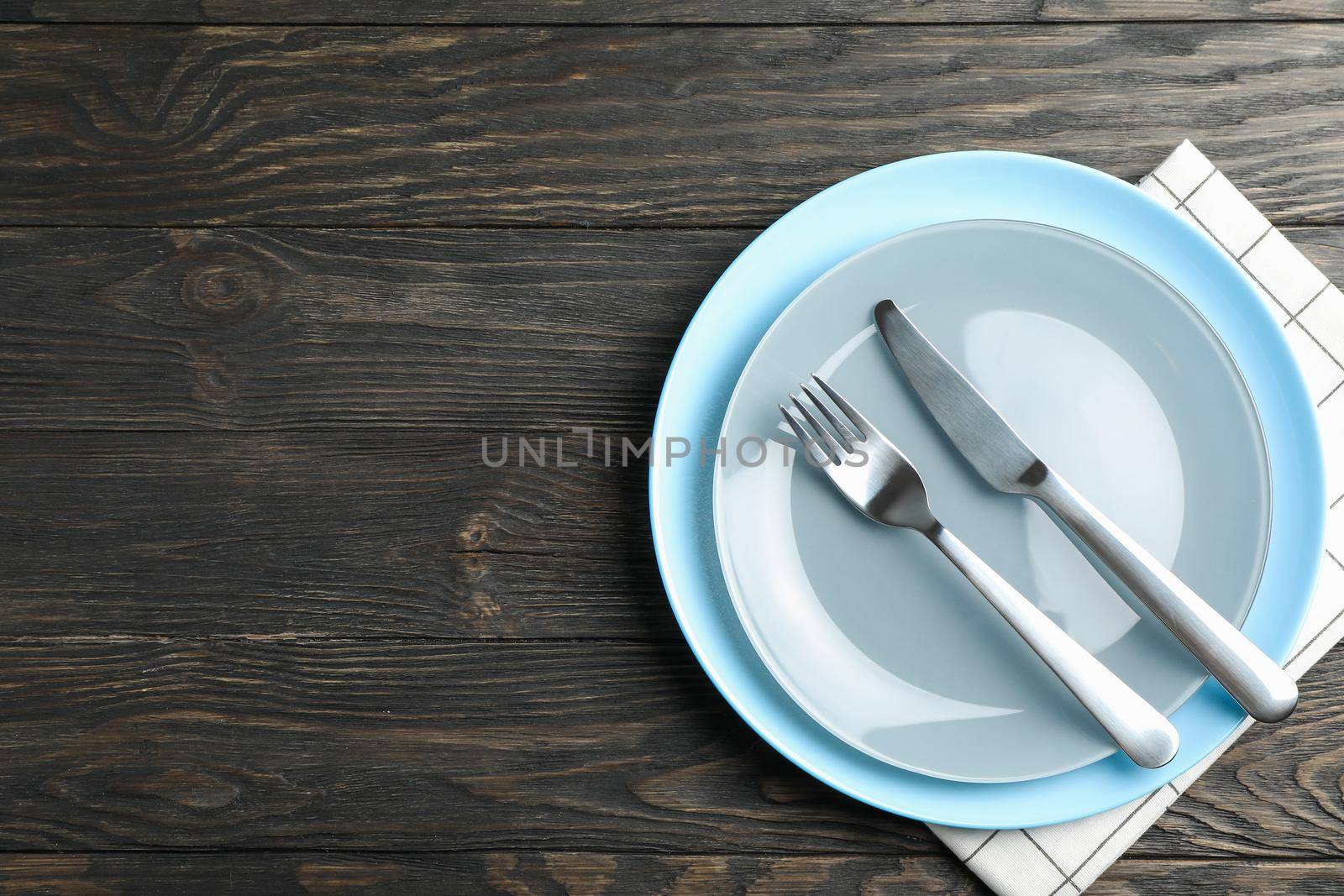 Kitchen towel with cutlery on wooden background, top view