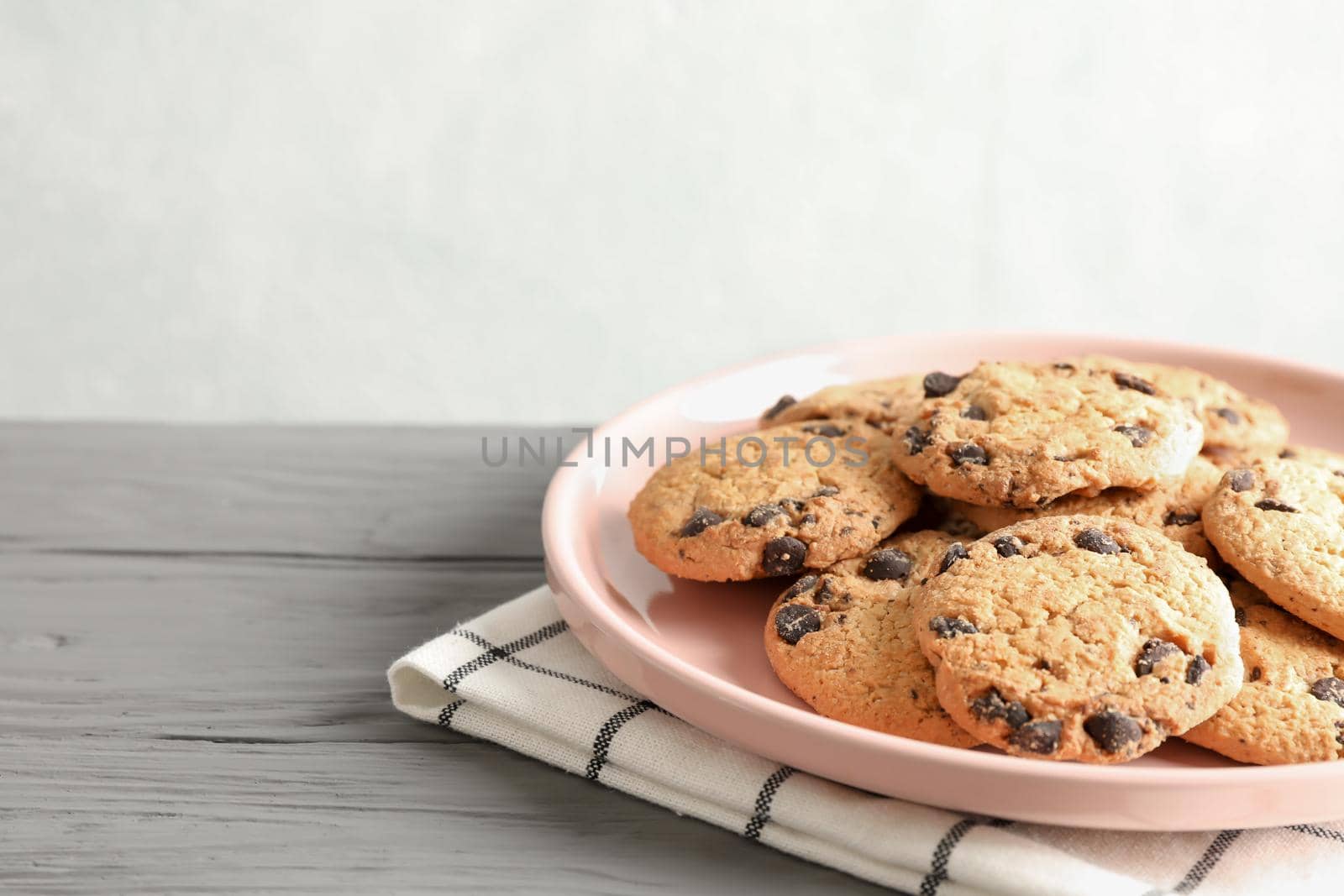 Plate with chocolate chip cookies and space for text on wooden table