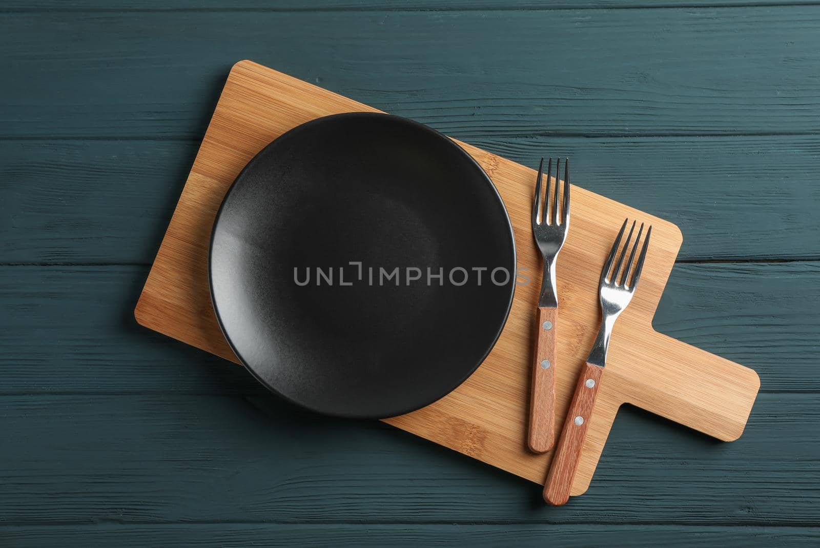 Cutting board and cutlery on wooden background, space for text