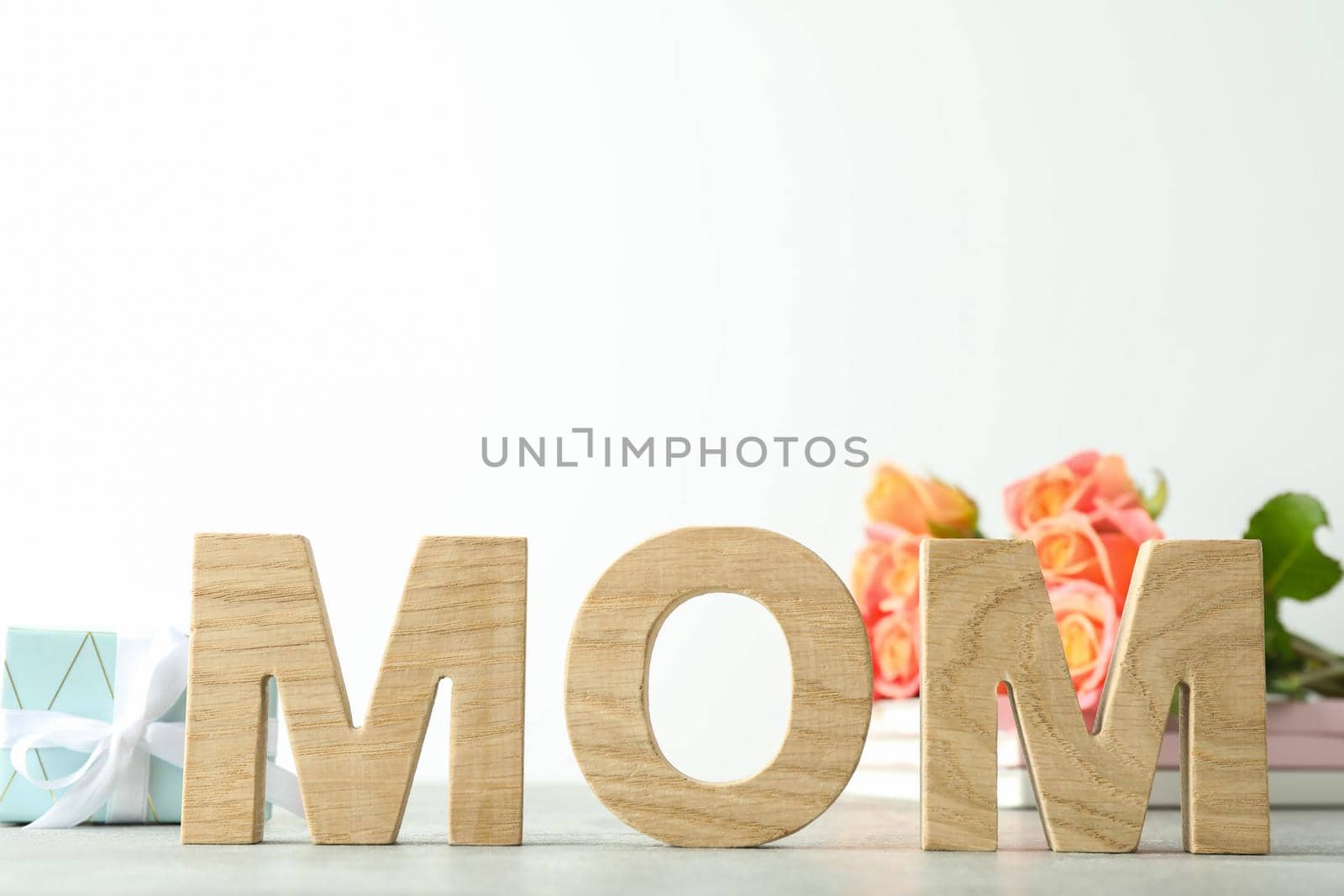 Inscription Mom, beautiful pink roses and gift on grey table against white background, space for text by AtlasCompany