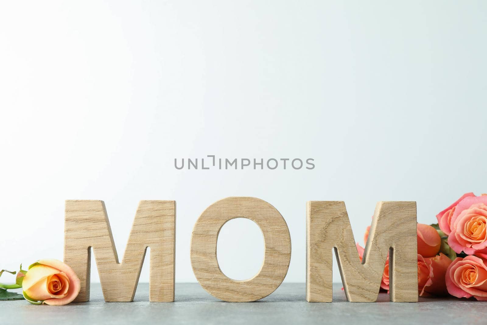 Inscription Mom, beautiful pink roses on grey table against white background, space for text