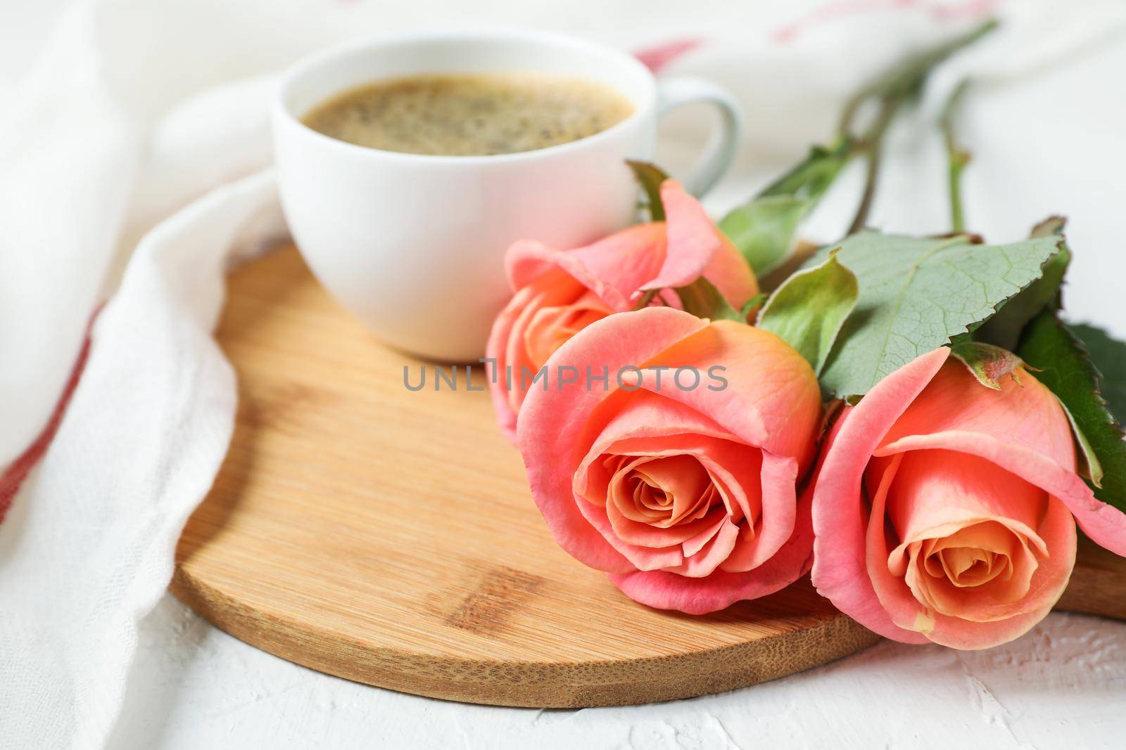 Composition with cup of coffee, roses and kitchen towel on white background, closeup