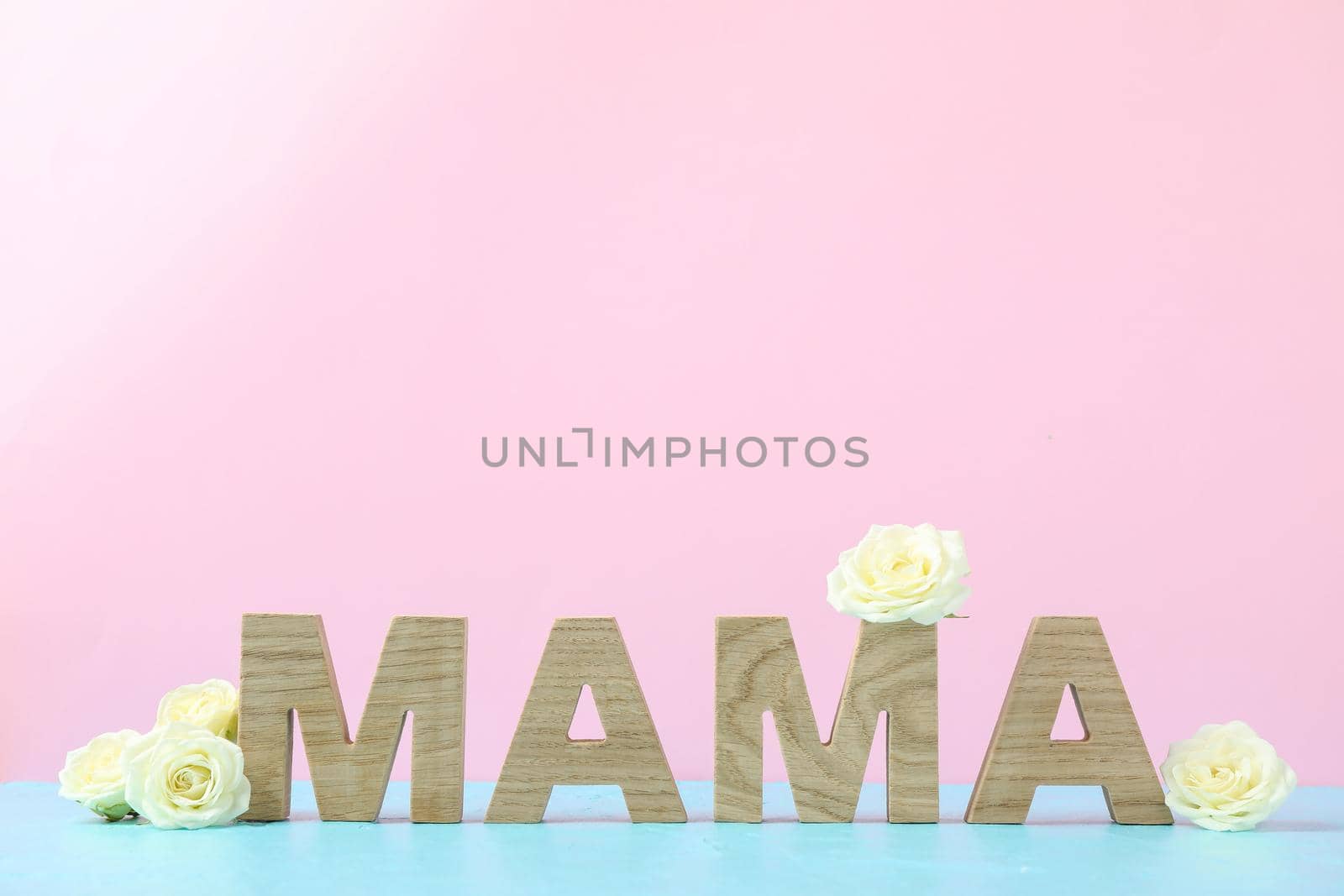 Inscription Mom with white roses on blue table against color background, space for text