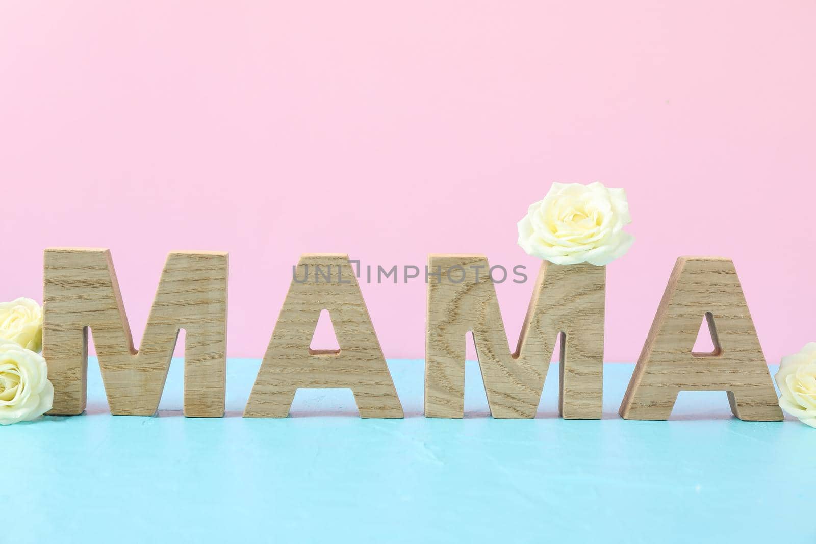 Inscription Mom with white roses on blue table against color background, space for text