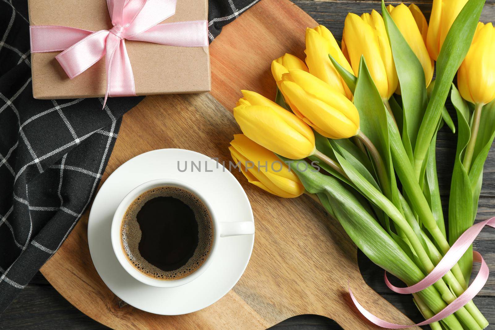 Beautiful tulips with notebooks and cup of coffee on wooden background, top view