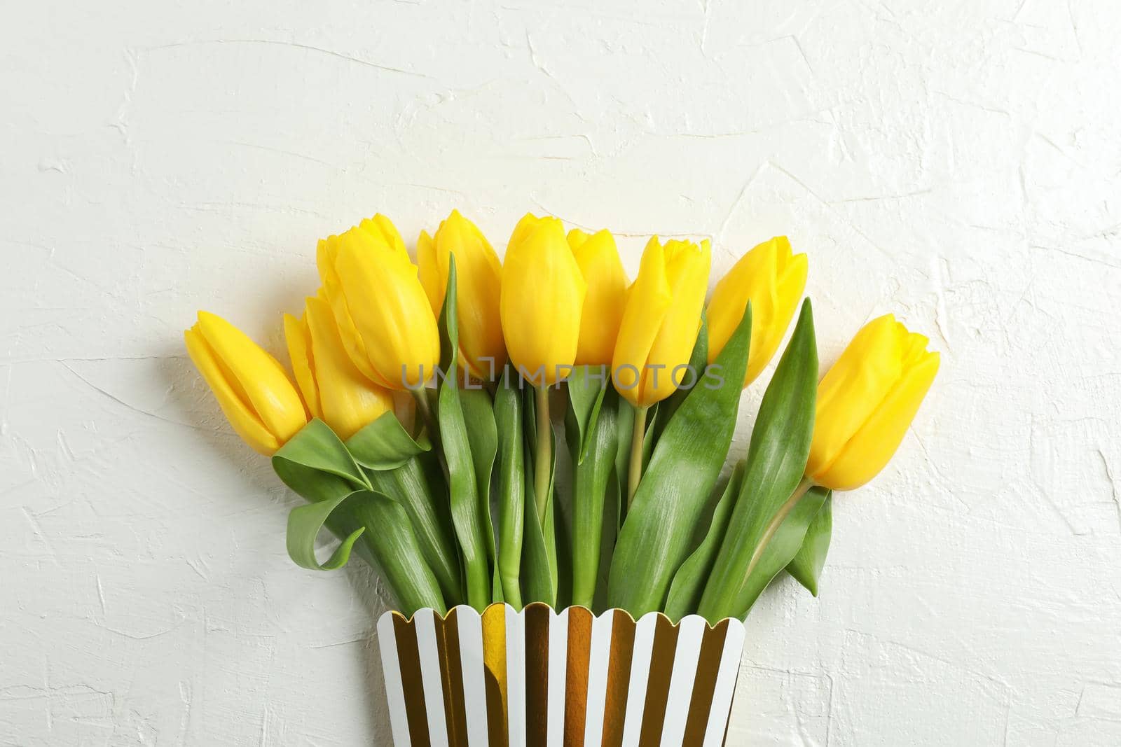 Beautiful fresh yellow tulips in cardboard box on light background