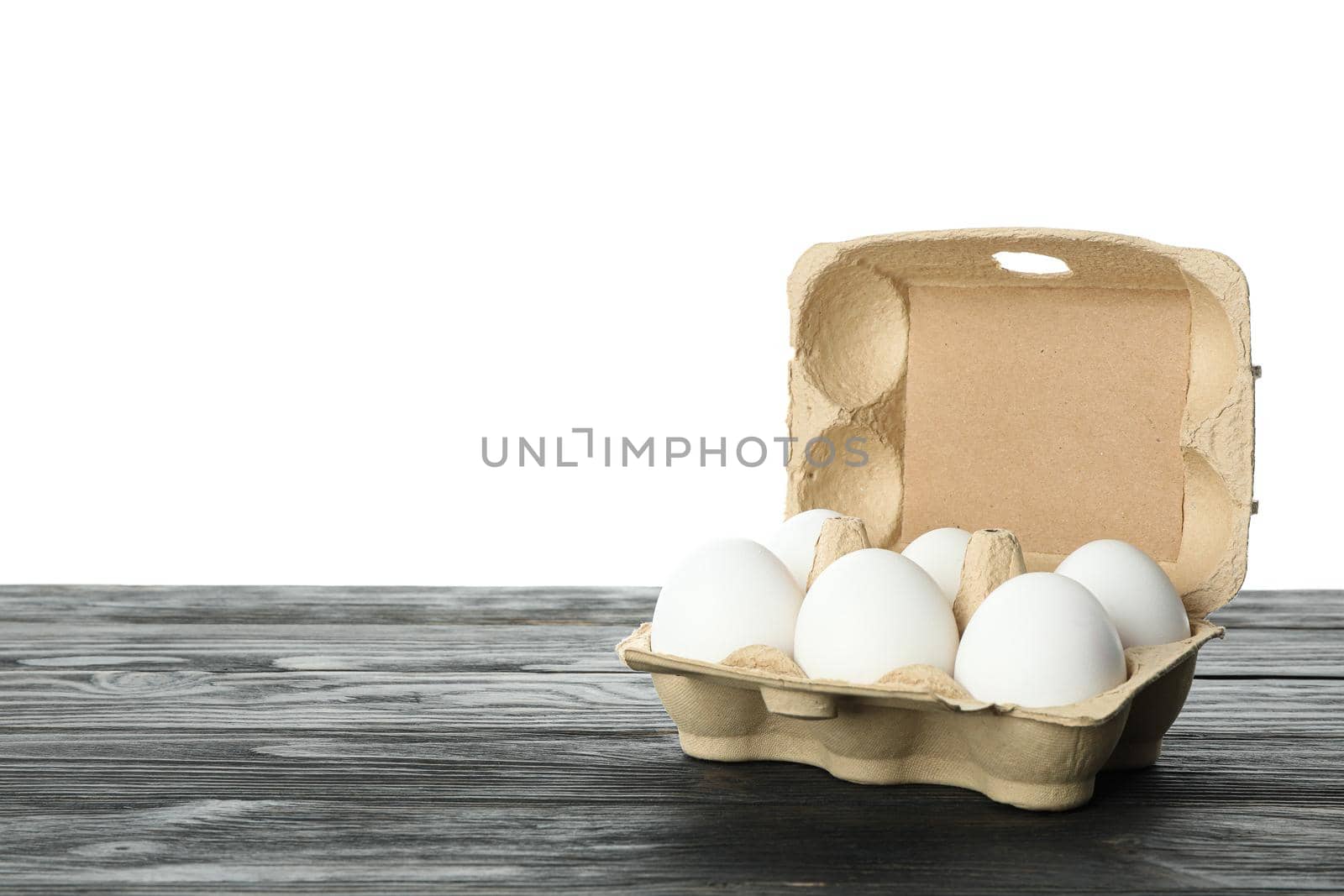 White chicken eggs in carton box on wooden table isolated on white background, space for text by AtlasCompany