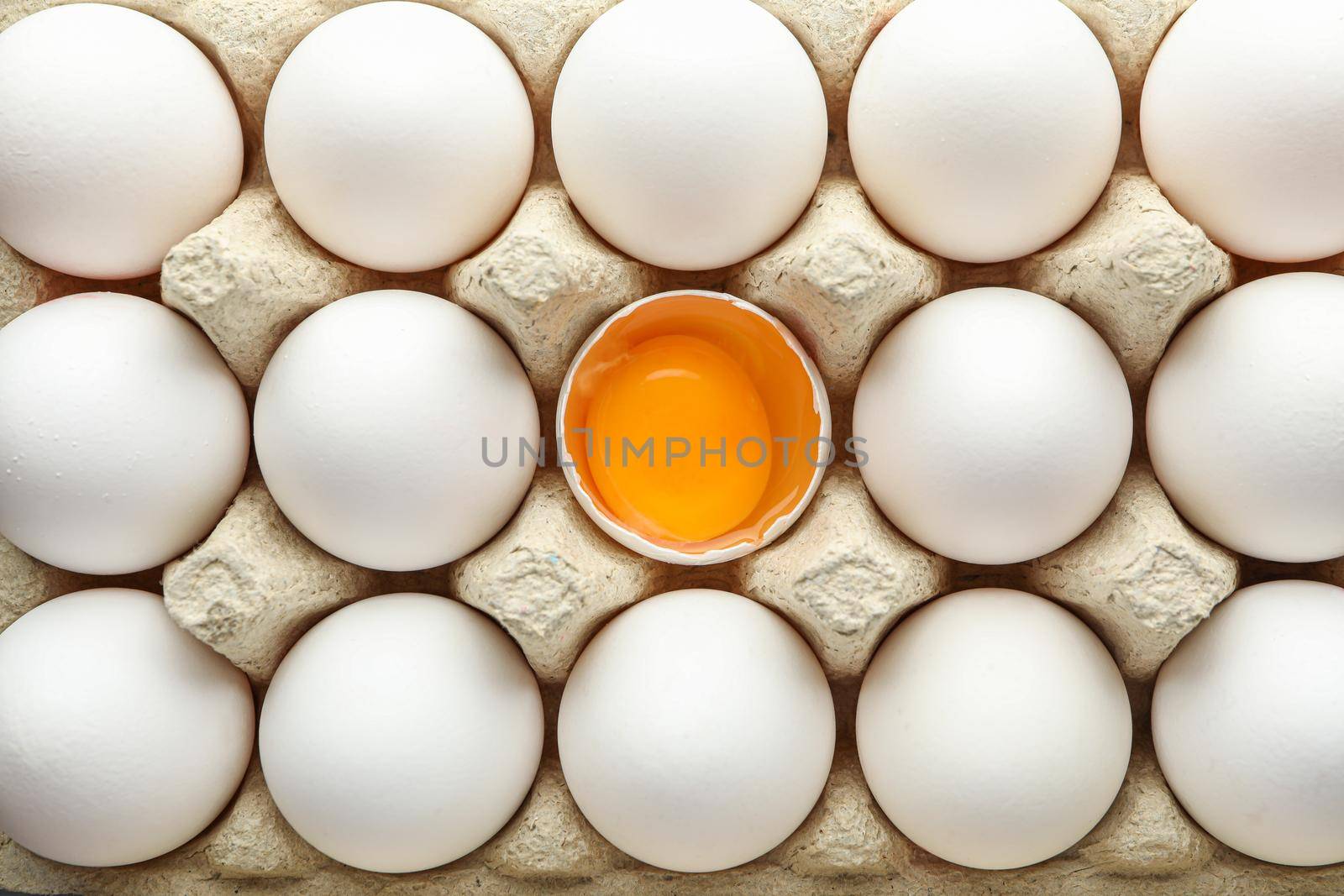 White chicken eggs in carton box as background, top view