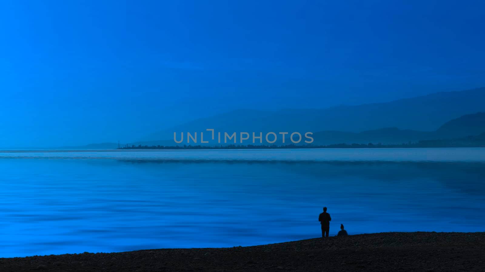 Seascape blue evening and silhouettes of people on the beach.