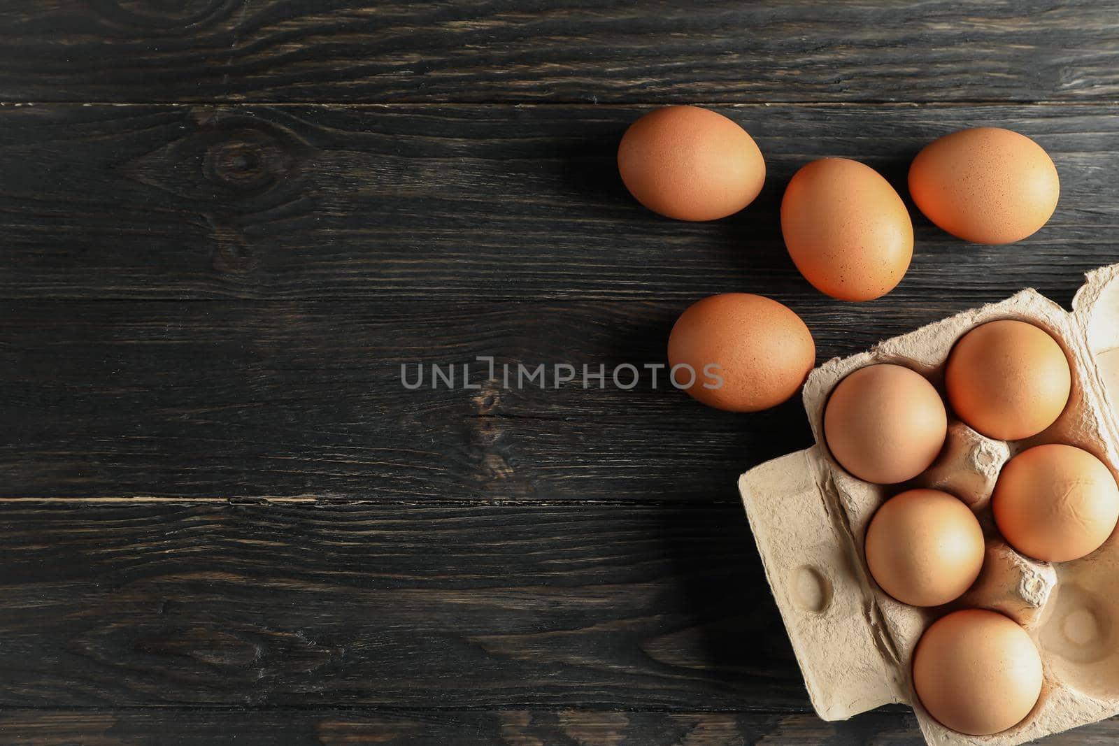 Chicken eggs in carton box on wooden background, space for text by AtlasCompany