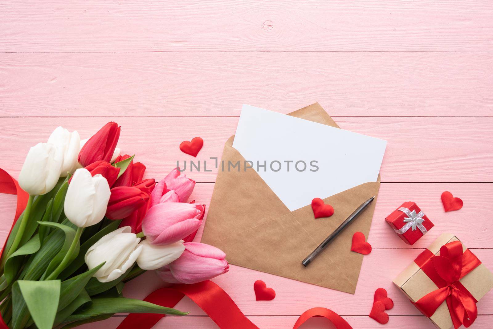 Frame mock up with Greeting card and envelope with colorful spring tulips top view over pink wooden background. Flat lay, top view.