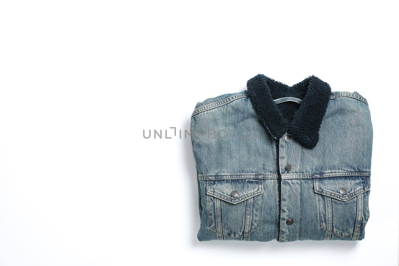 Folded denim jacket on white background, space for text by AtlasCompany