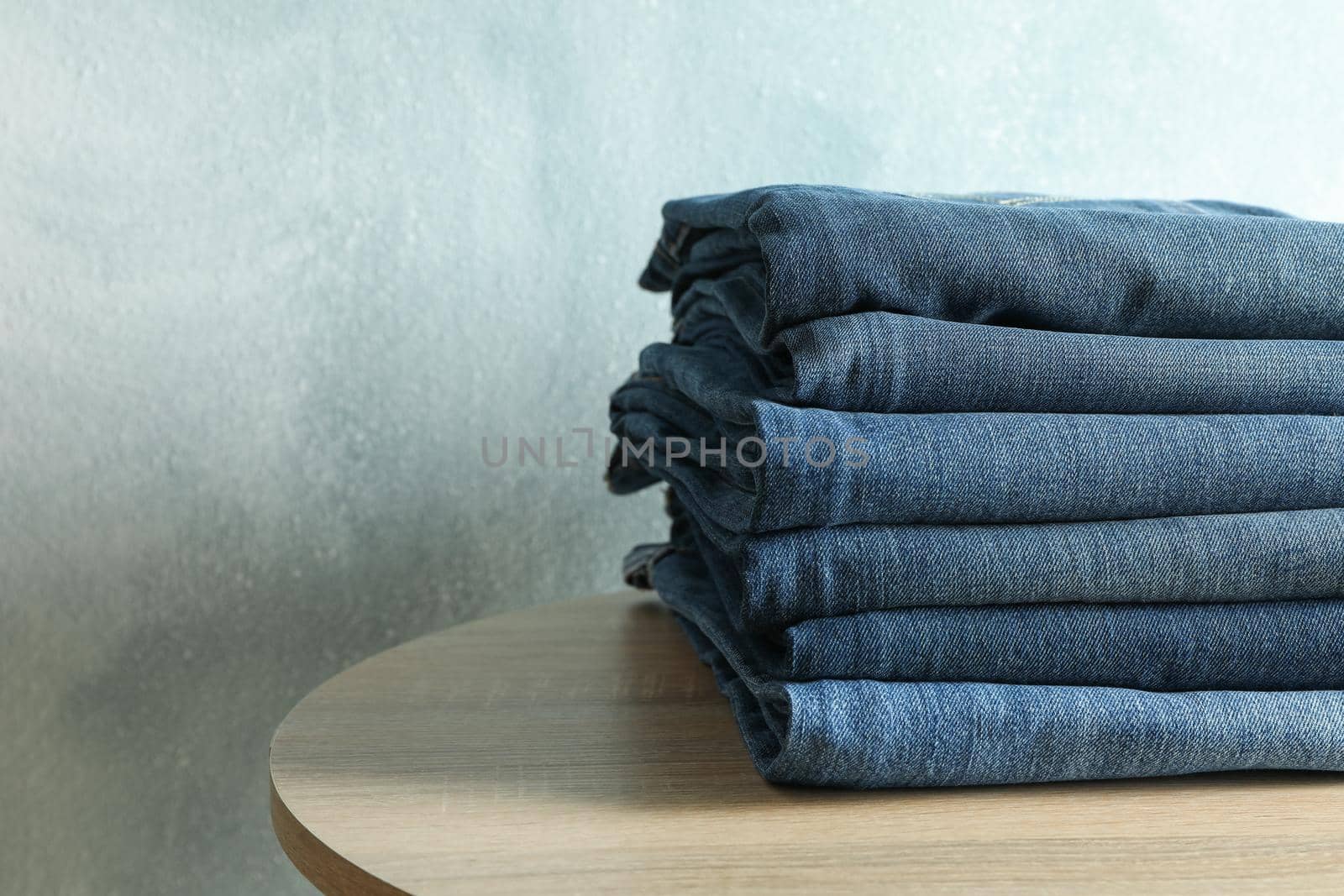 Stack of jeans pants on wooden table, space for text by AtlasCompany