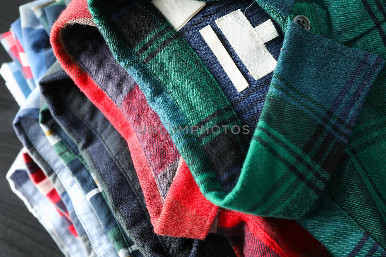 Stack of different shirts on black table, close up by AtlasCompany
