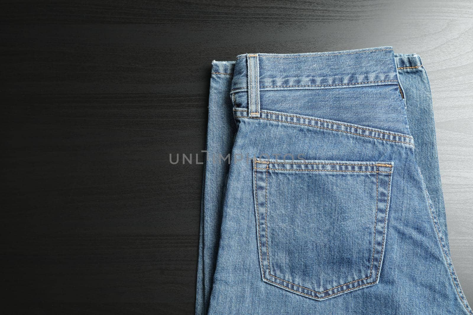 Classic jeans on black background, space for text