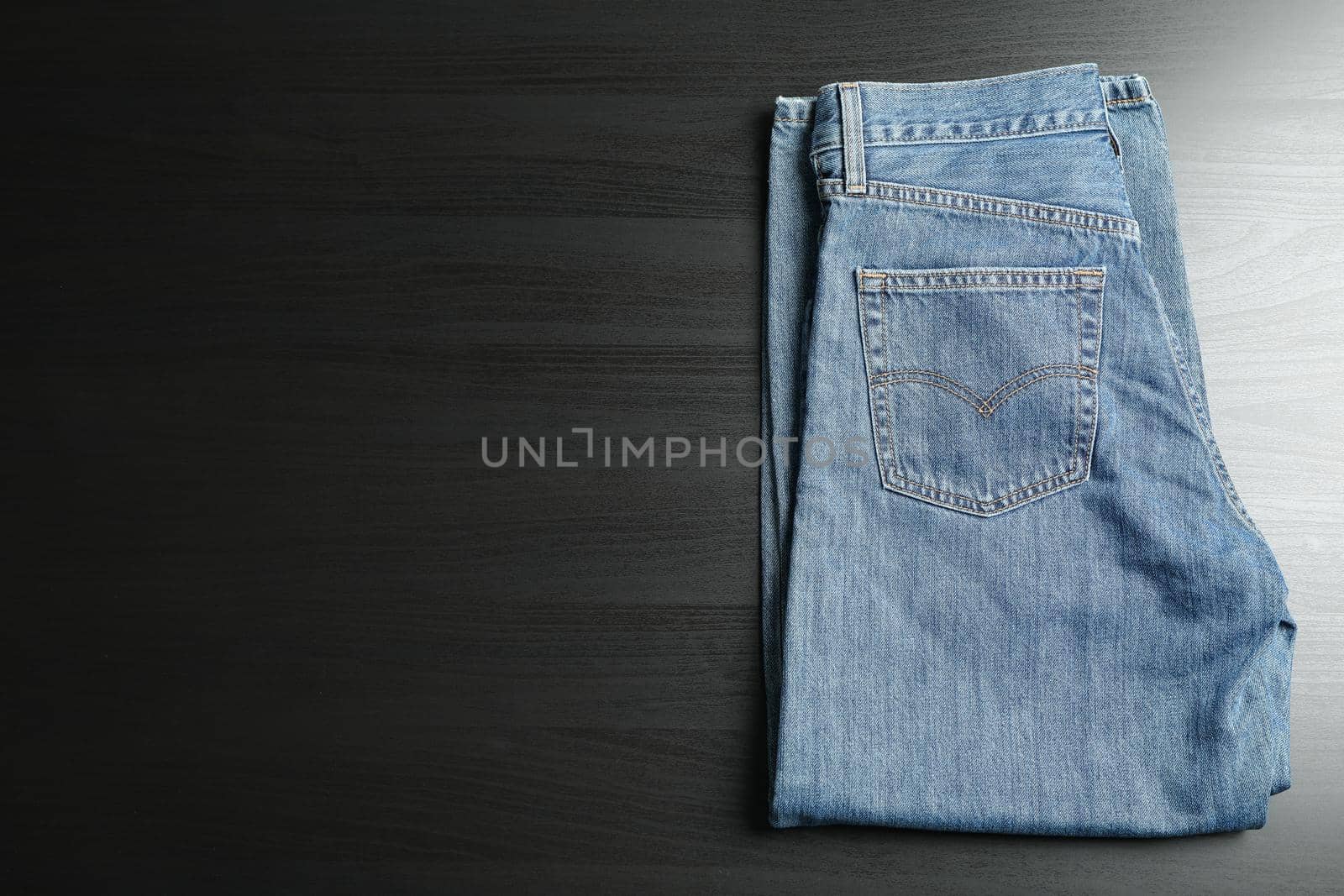 Folded jeans on black table, space for text