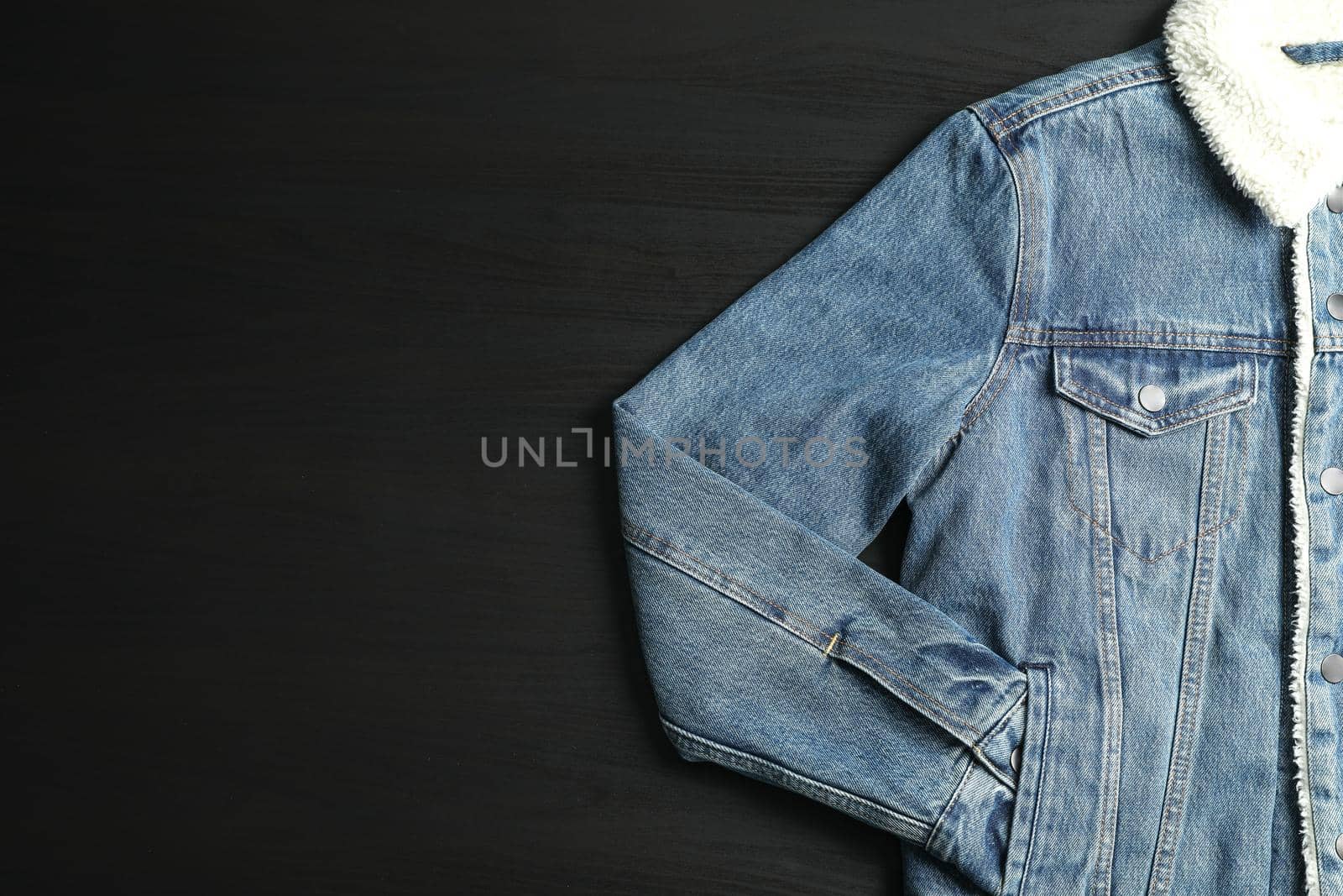 Denim jacket on black background, space for text by AtlasCompany