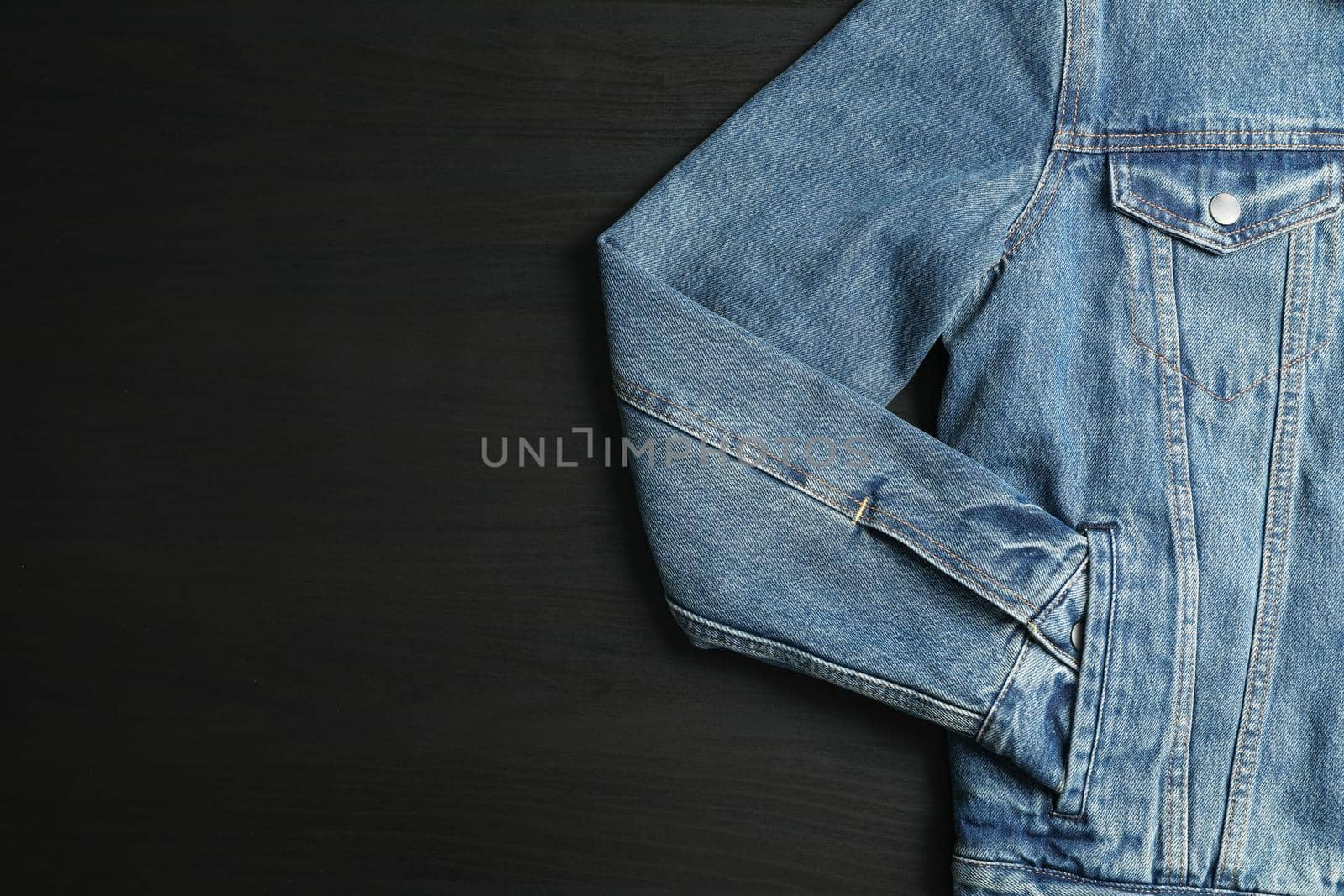 Denim jacket on black background, space for text by AtlasCompany